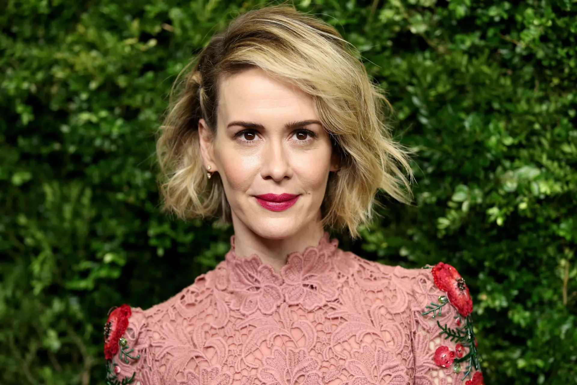Sarah Paulson em um tapete vermelho, com um sorriso confiante.