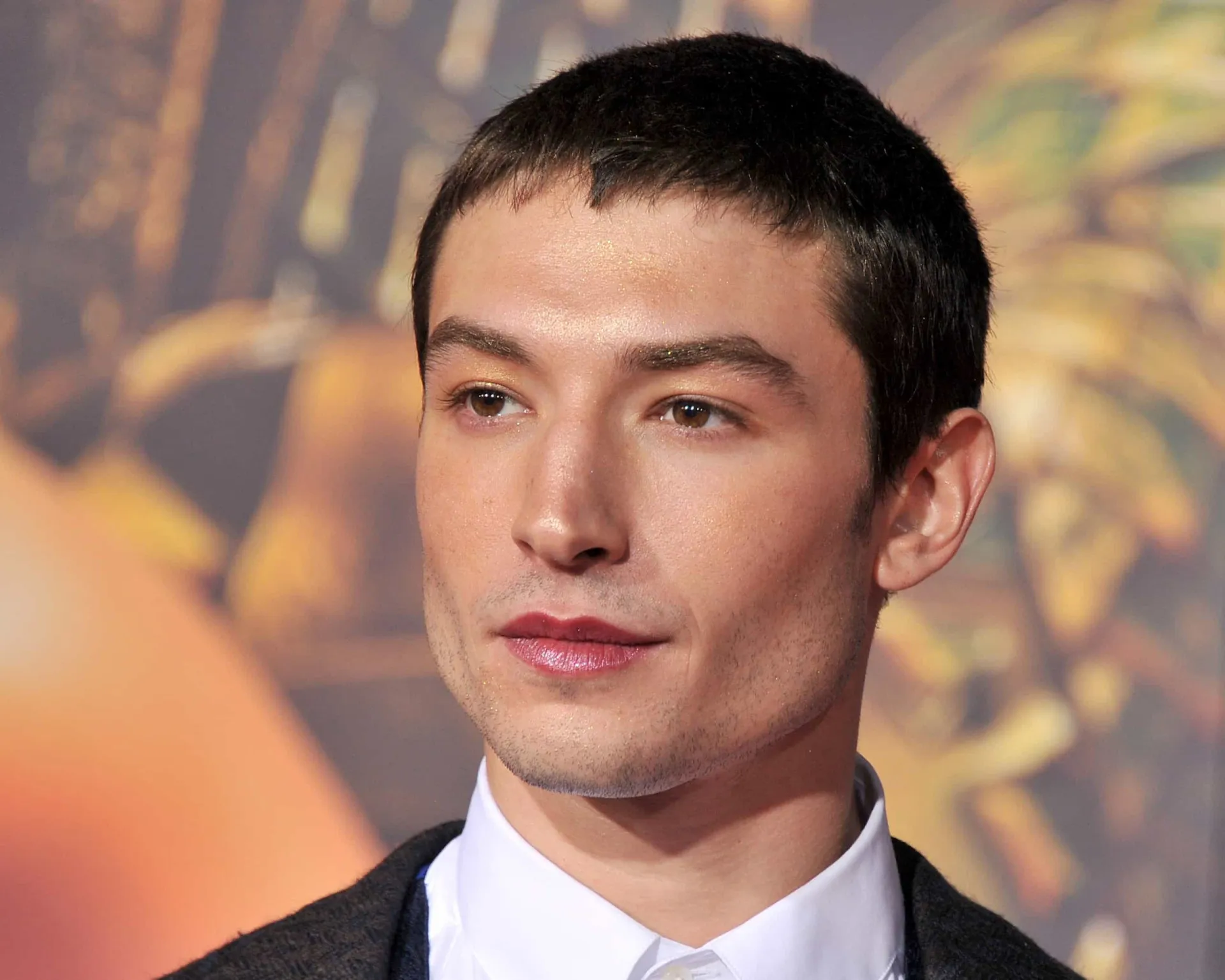 Ezra Miller com uma expressão intensa e maquiagem marcante.