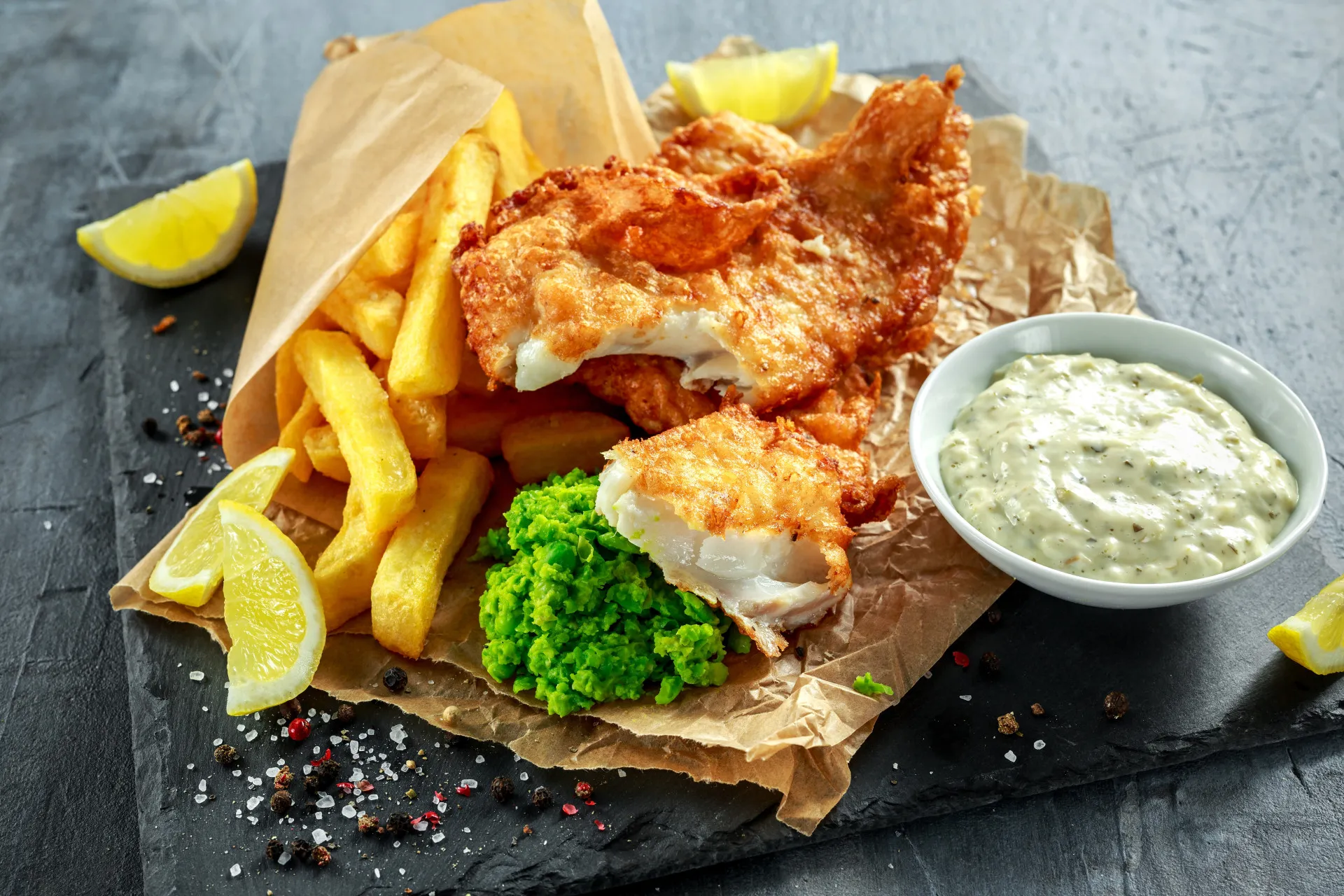 Prato clássico de fish and chips, peixe frito com batatas, servido em papel jornal.