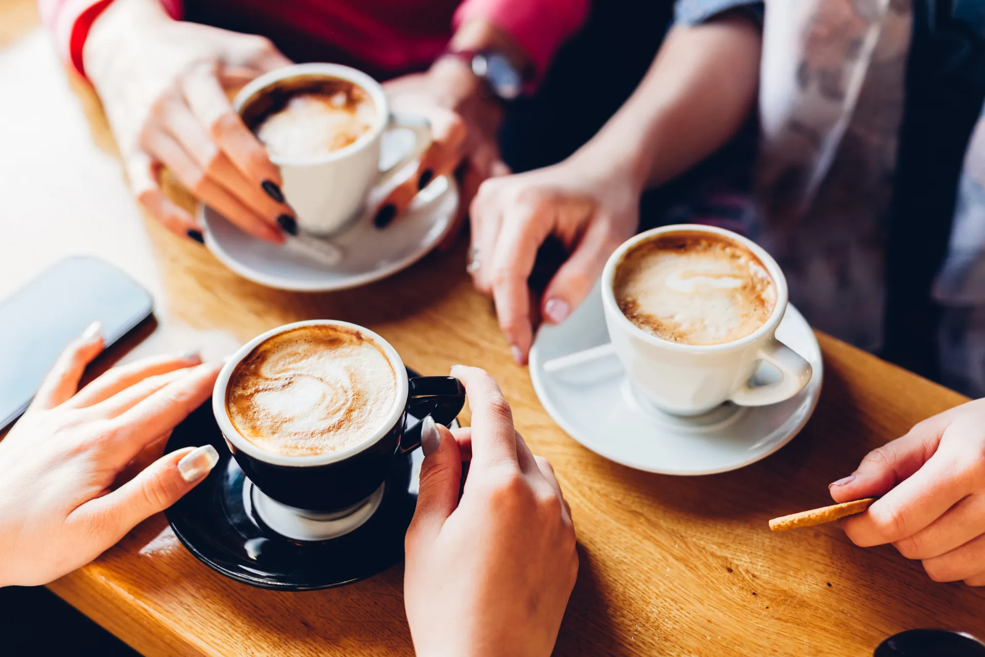 Uma xícara de café quente com grãos de café espalhados ao redor.