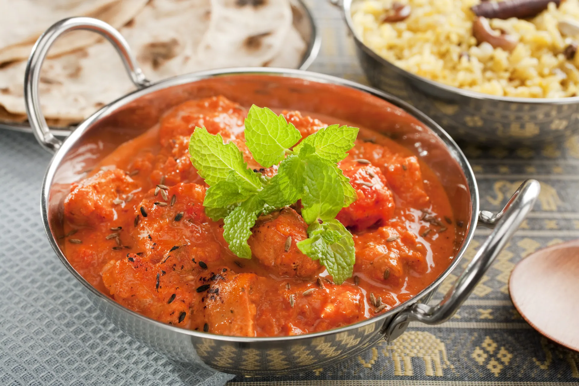 Uma tigela de frango tikka masala cremoso e alaranjado, servido com coentro fresco.