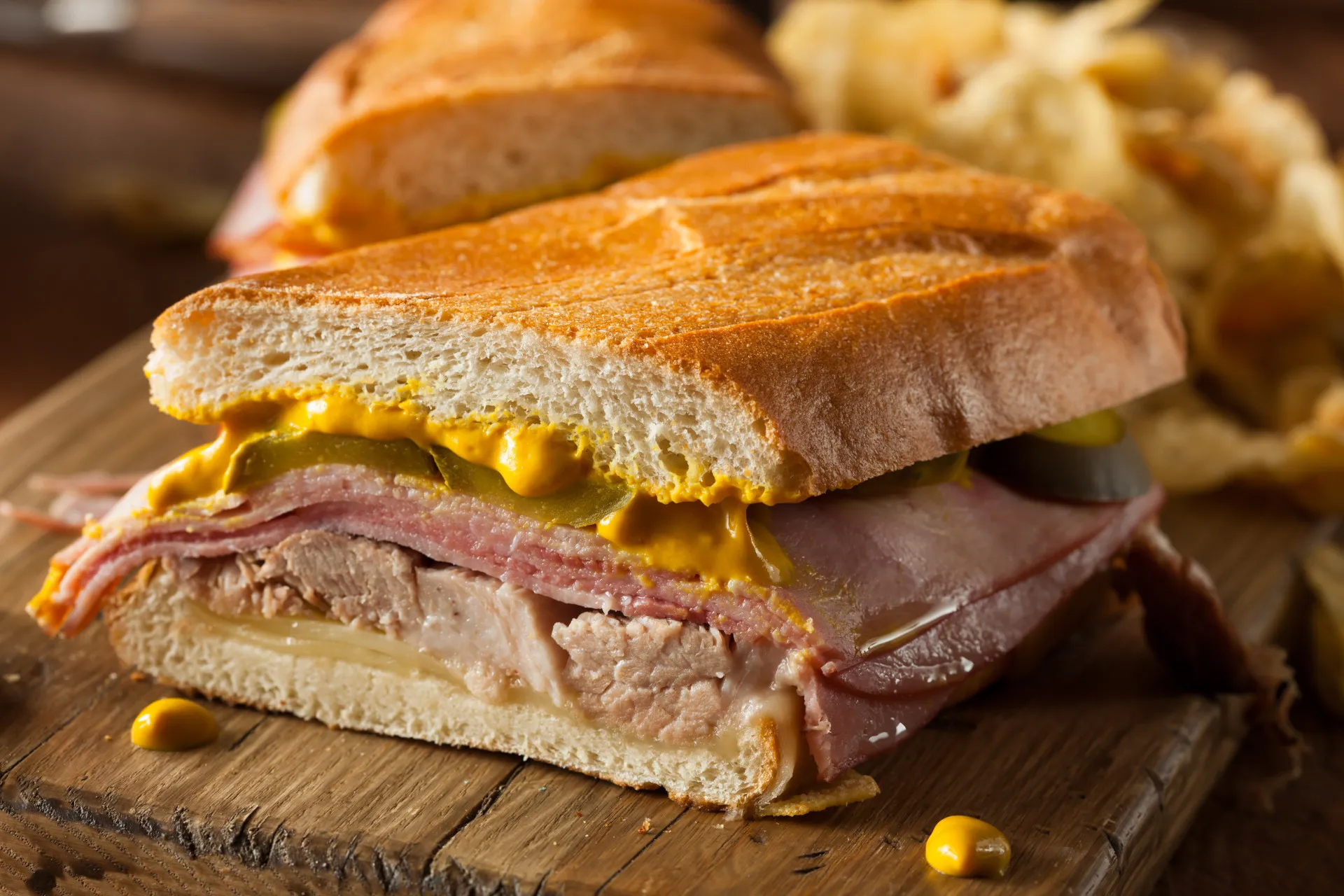 Um sanduíche cubano prensado, com camadas de porco, presunto, queijo e picles.