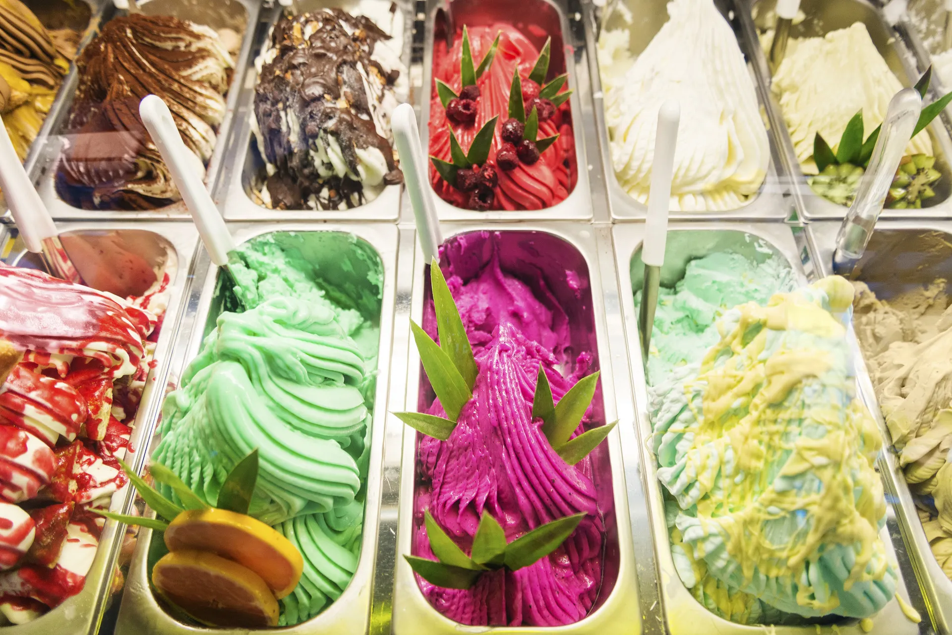 Mão segurando um gelato italiano cremoso em uma casquinha, com uma cidade italiana ao fundo.