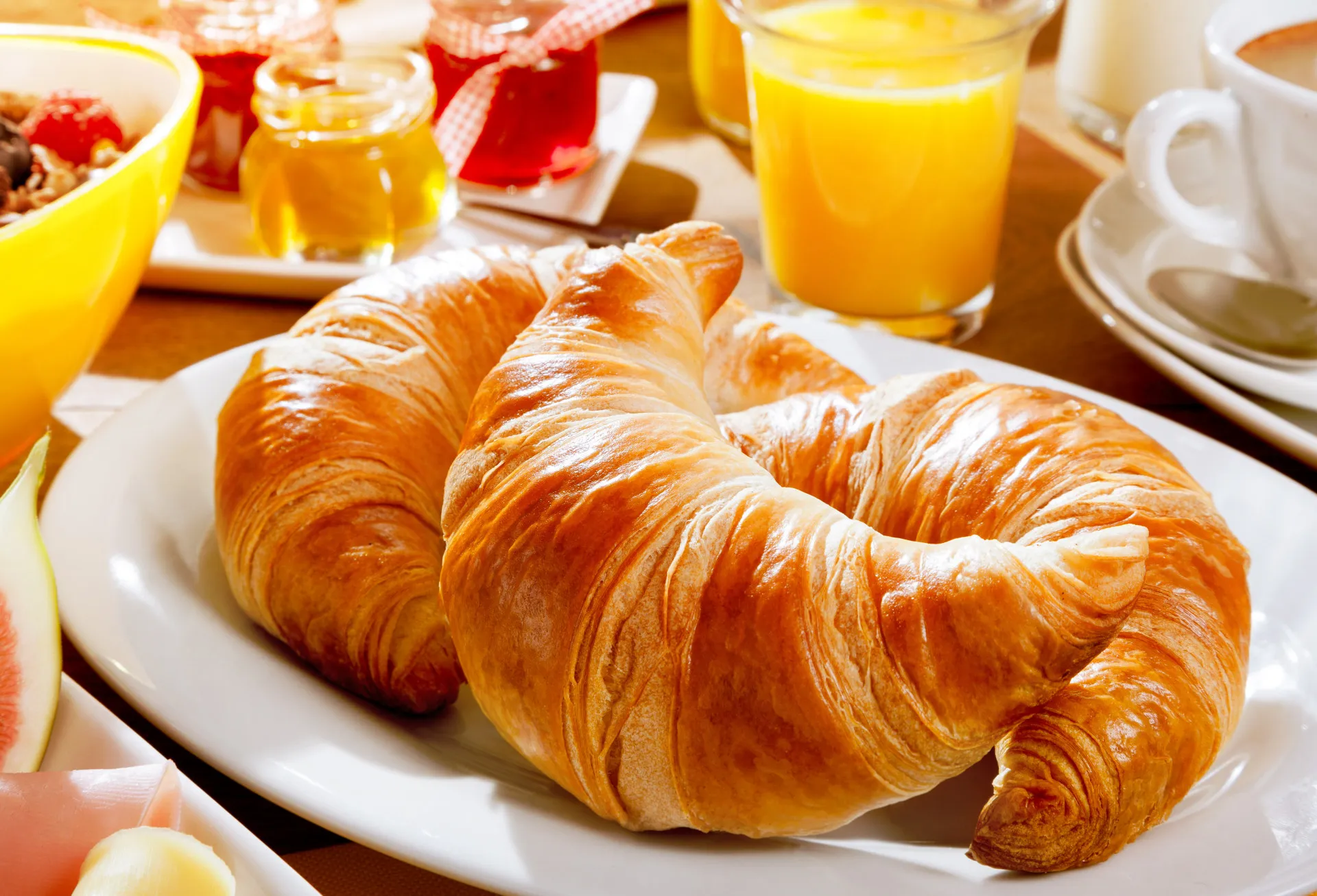 Croissants dourados e amanteigados em uma cesta, símbolo da confeitaria francesa.