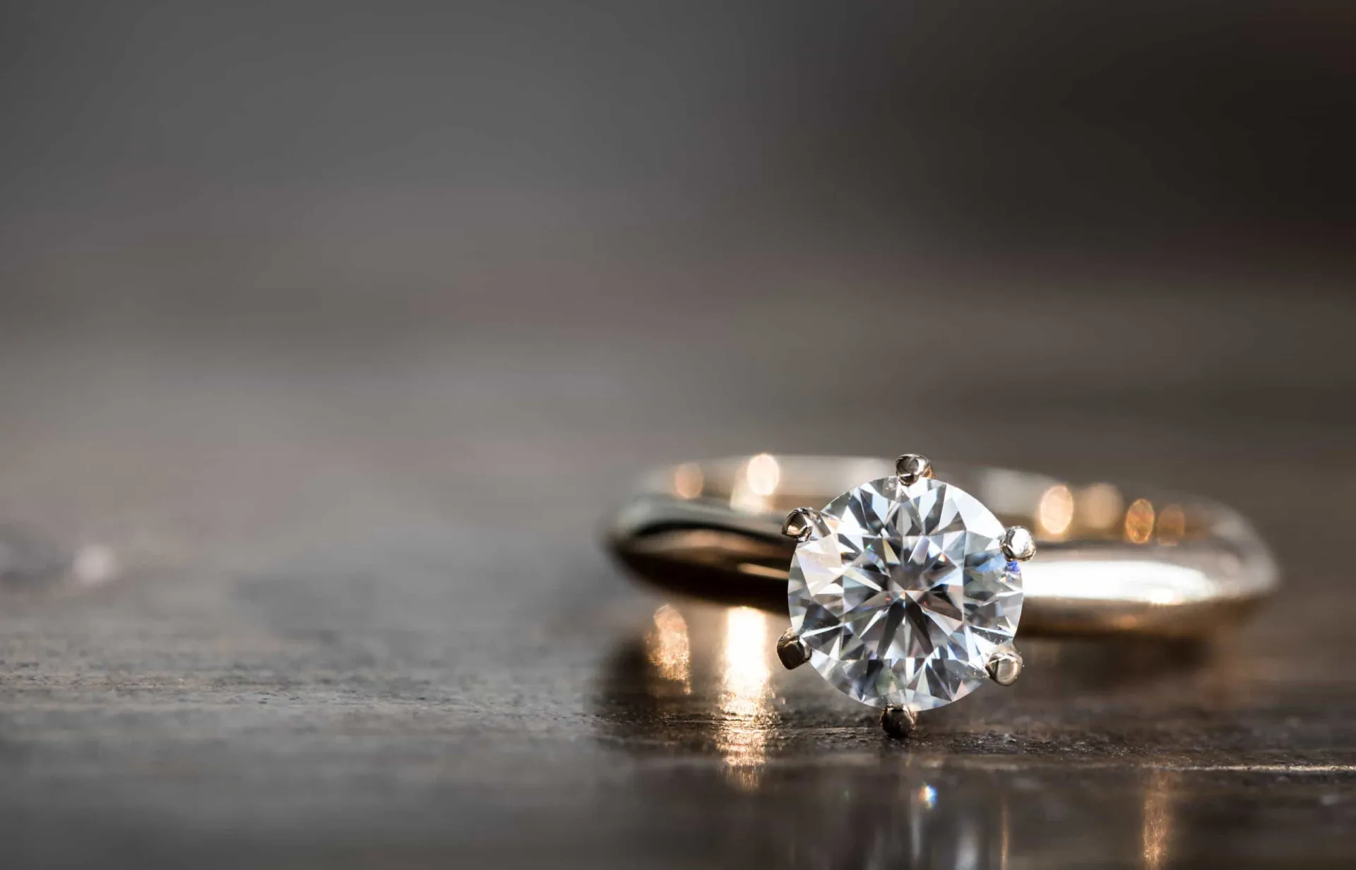 Close de um anel de noivado com diamante sendo colocado no dedo anelar de uma mulher.