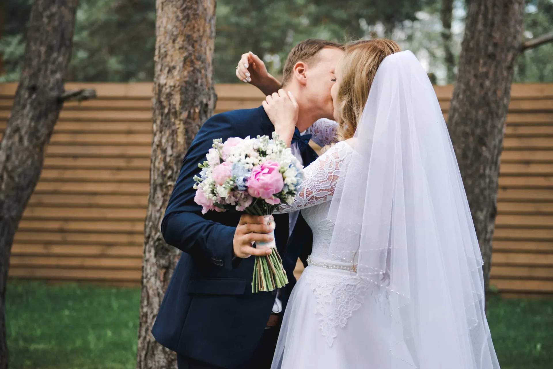 Noivos se beijando no altar após serem declarados casados, com os convidados ao fundo.