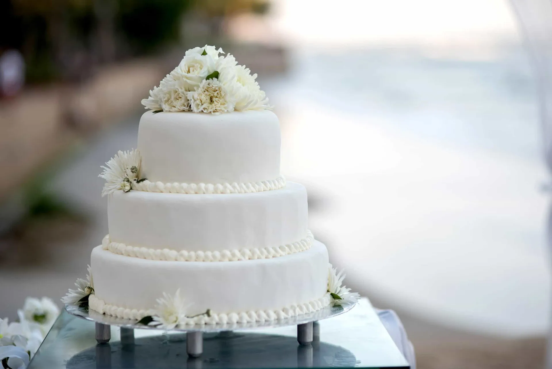 Bolo de casamento de vários andares, decorado com flores brancas e detalhes elegantes.