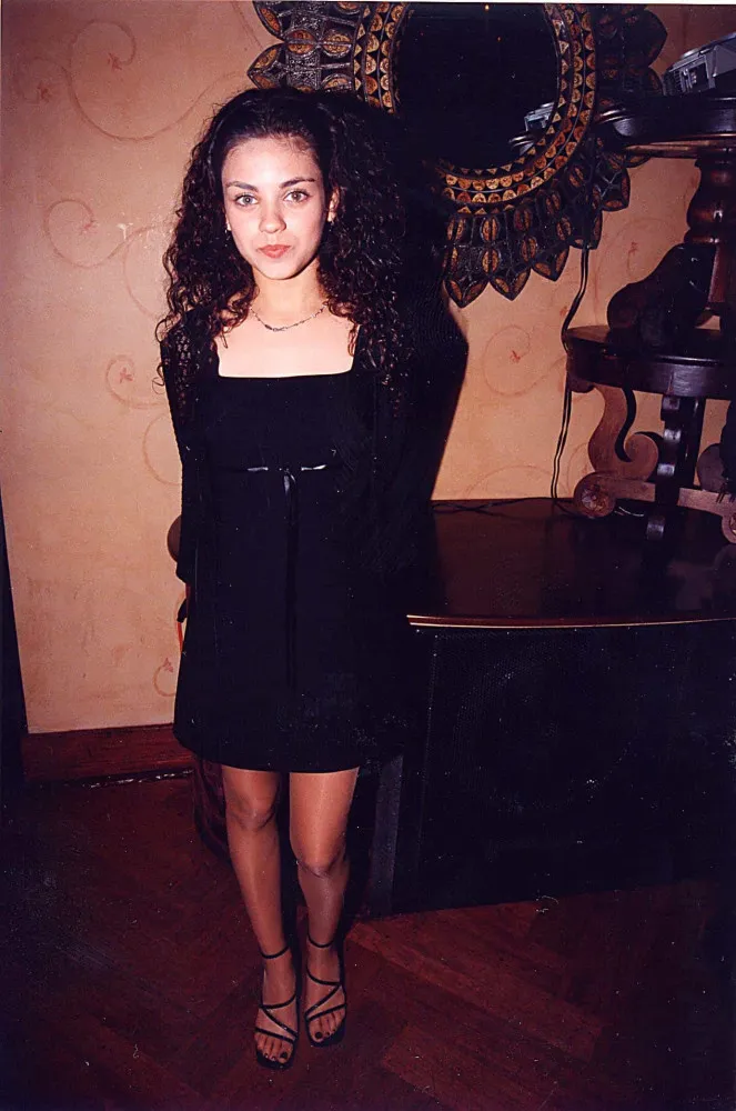 A atriz Mila Kunis em um evento, famosa desde a adolescência.