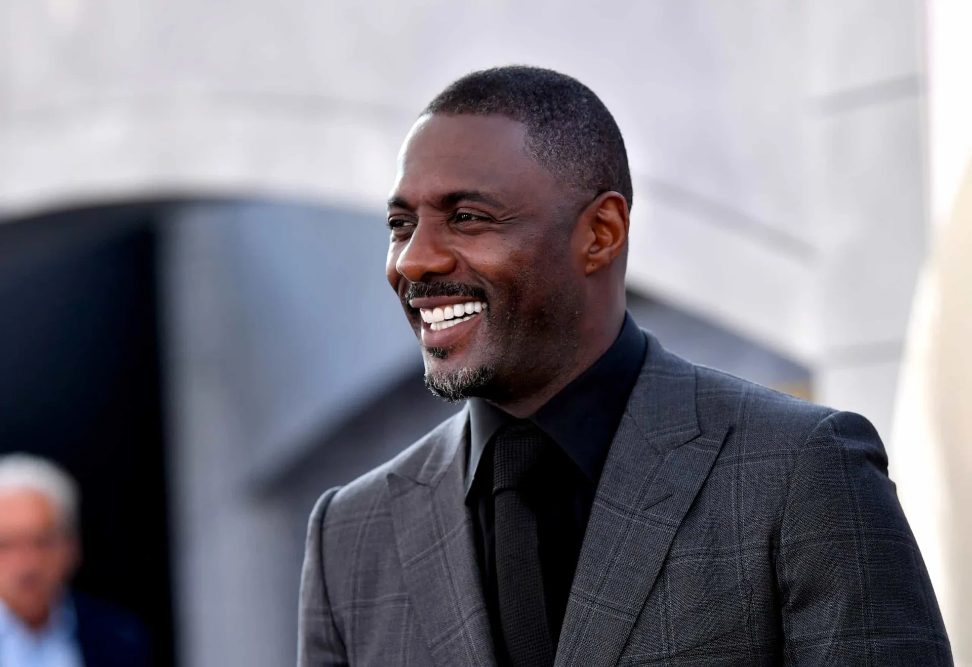 Idris Elba olhando para a câmera com uma expressão séria e confiante.