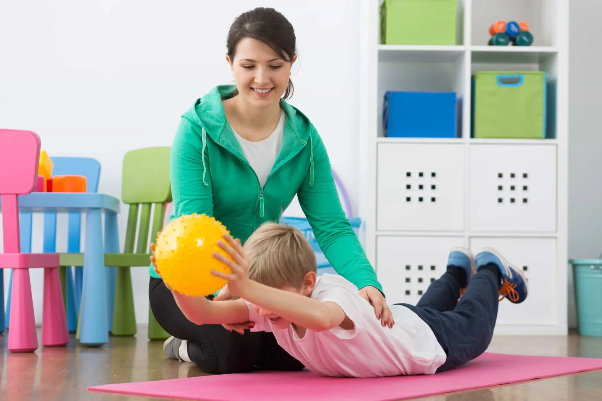 Fisioterapeuta auxiliando uma criança com exercícios de mobilidade.