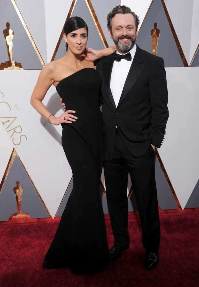 Kate Beckinsale e Sarah Silverman posando juntas em um tapete vermelho, como grandes amigas.