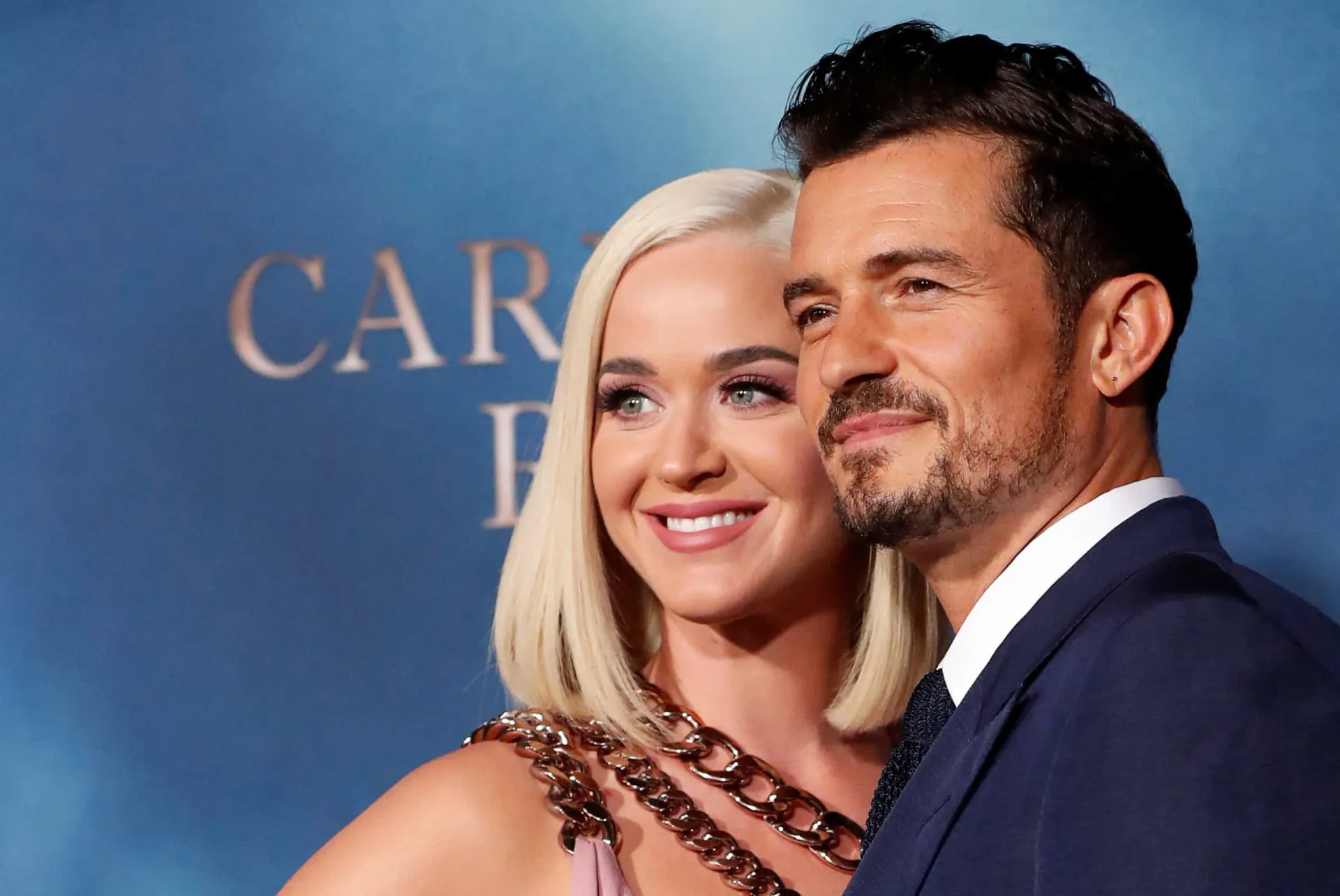 Katy Perry e Miranda Kerr posando juntas em um evento, com sorrisos cúmplices.