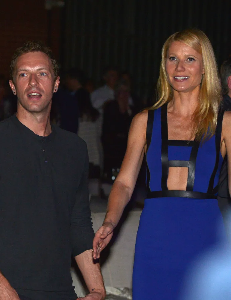 Gwyneth Paltrow, Brad Falchuk e Chris Martin juntos em um evento, demonstrando entrosamento.