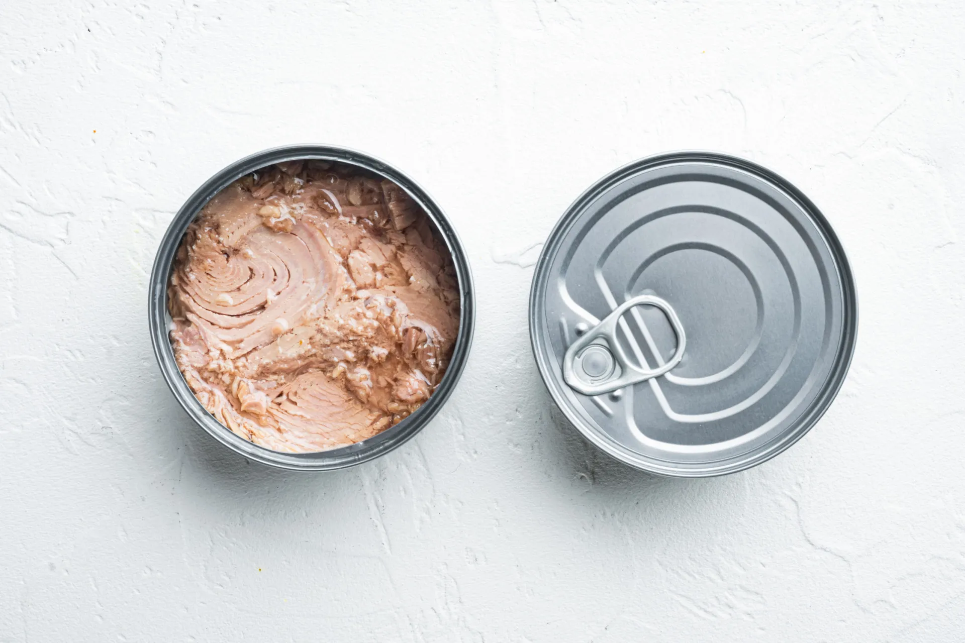 Várias latas de atum empilhadas, mostrando diferentes marcas e tipos.