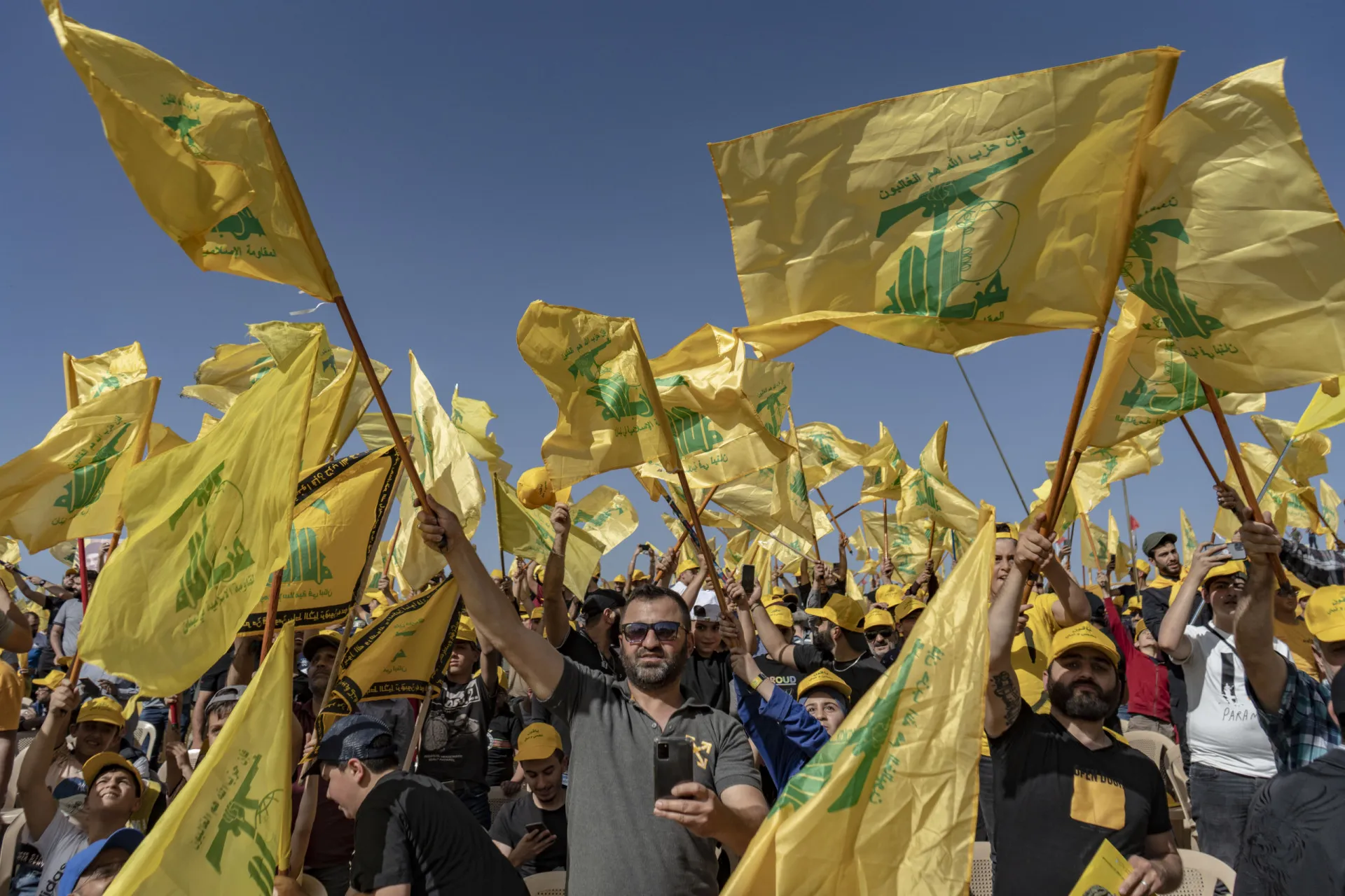 Militantes do Hezbollah em uma marcha, segurando bandeiras do grupo.