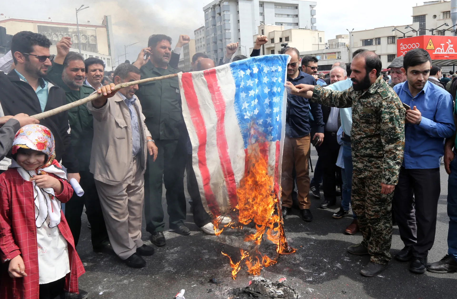 Uma multidão de iranianos agitando bandeiras do Irã em um comício nacionalista.