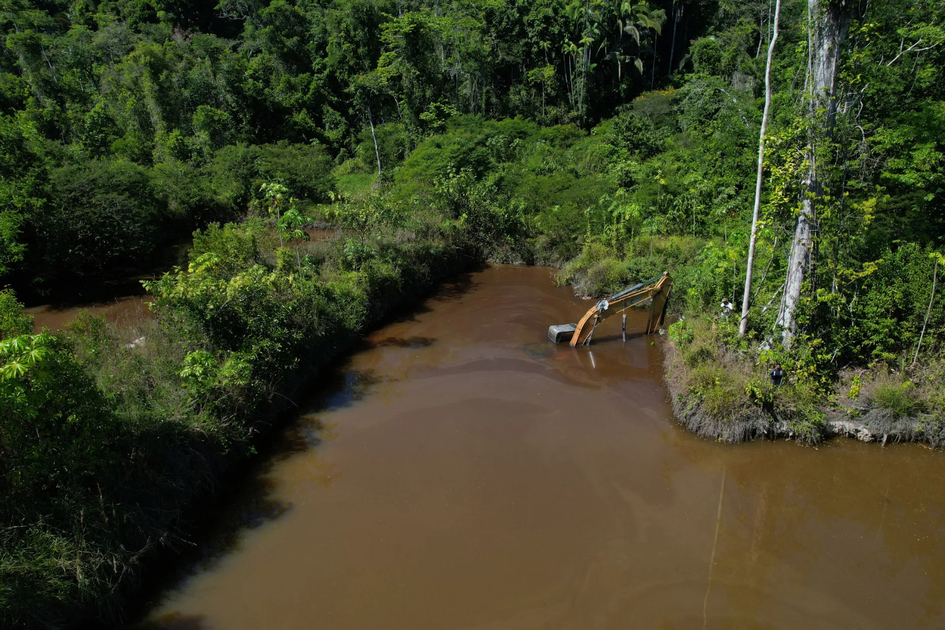Garimpo ilegal em um rio da Amazônia, com água barrenta e equipamentos de mineração.
