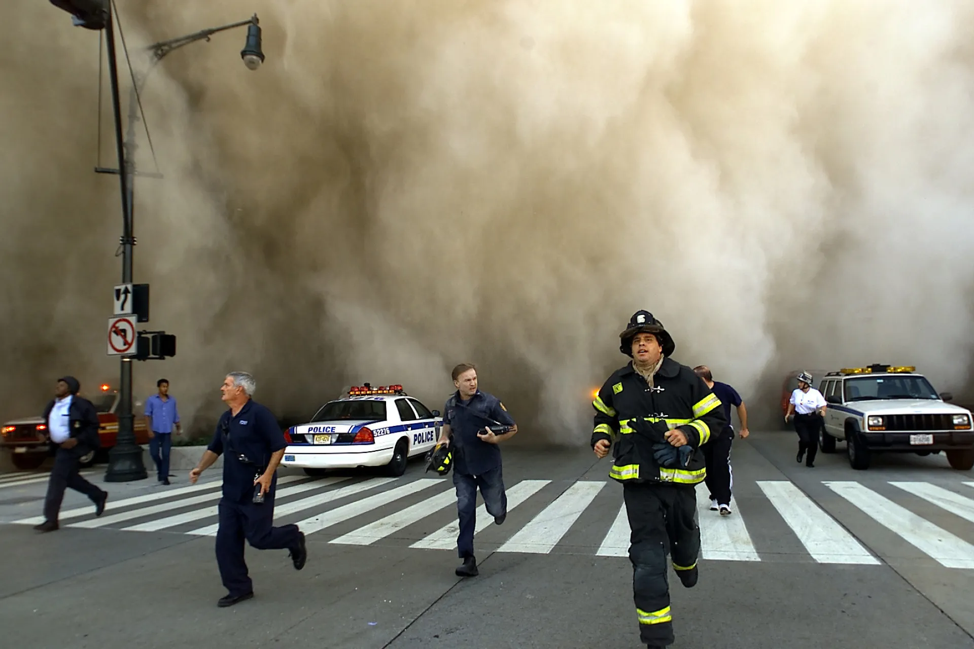 Pessoas cobertas de poeira e cinzas caminhando pelas ruas de Nova York após o colapso das torres.