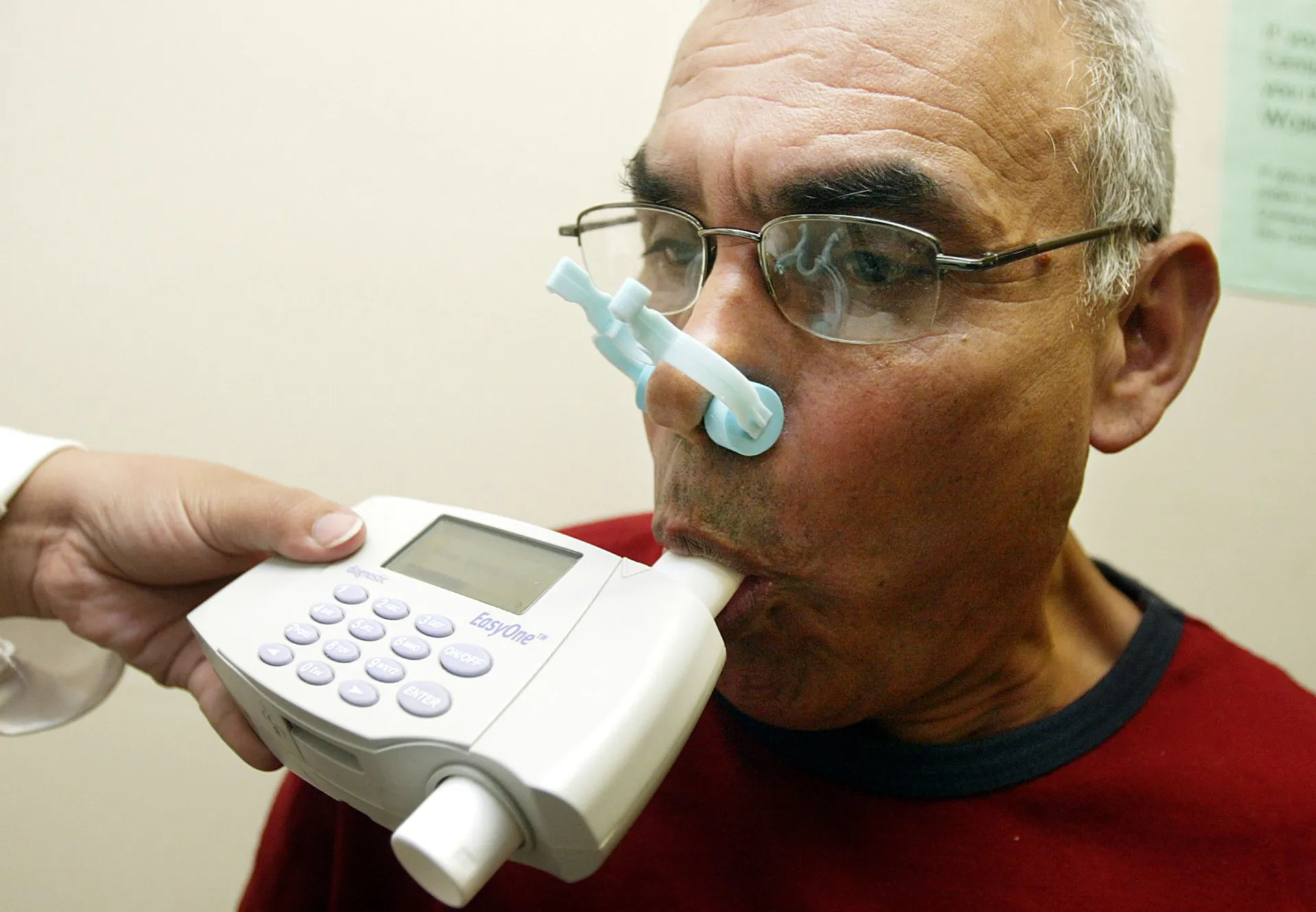 Pessoa usando um inalador para asma, representando dificuldades respiratórias.