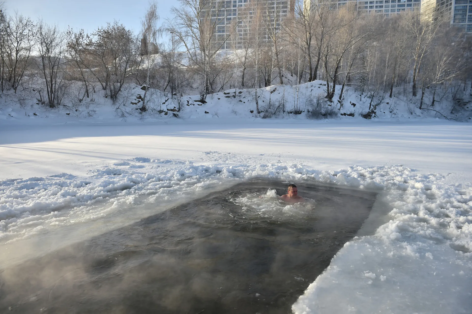Sinalização de rua em Moscou escrita em alfabeto cirílico, com a arquitetura da cidade ao fundo.