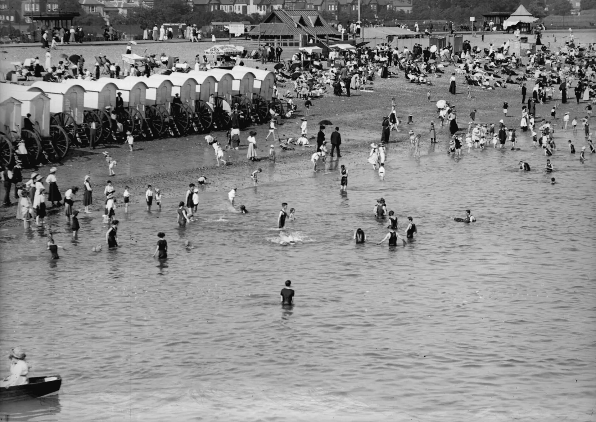 Britânicos em trajes de banho de época em uma praia durante uma onda de calor no início do século XX.