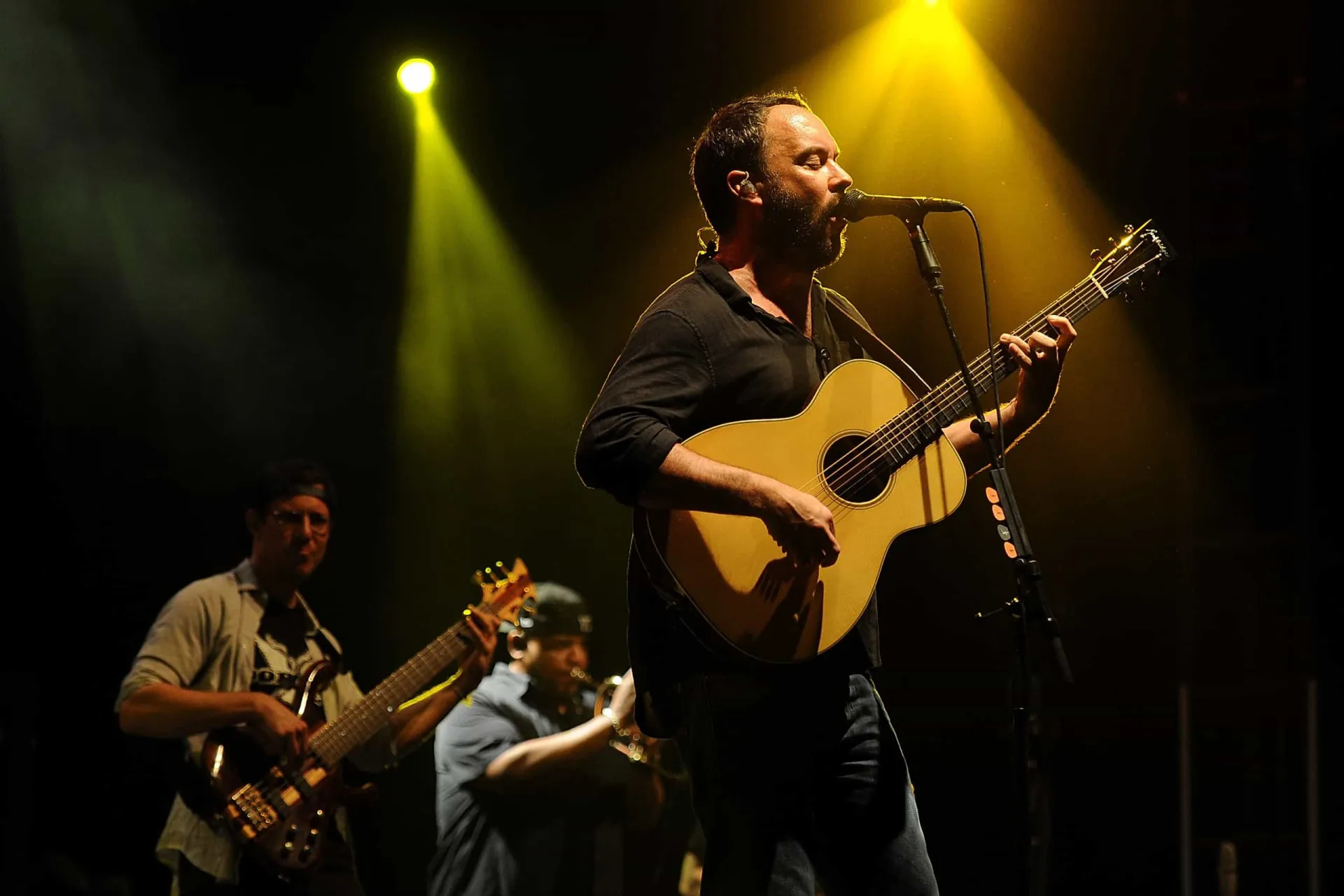 Dave Matthews cantando e tocando violão durante uma apresentação intimista.