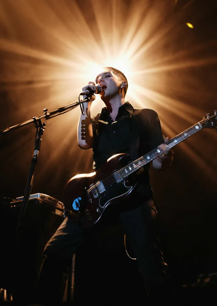 Brian Molko, vocalista da banda Placebo, cantando intensamente durante um show.