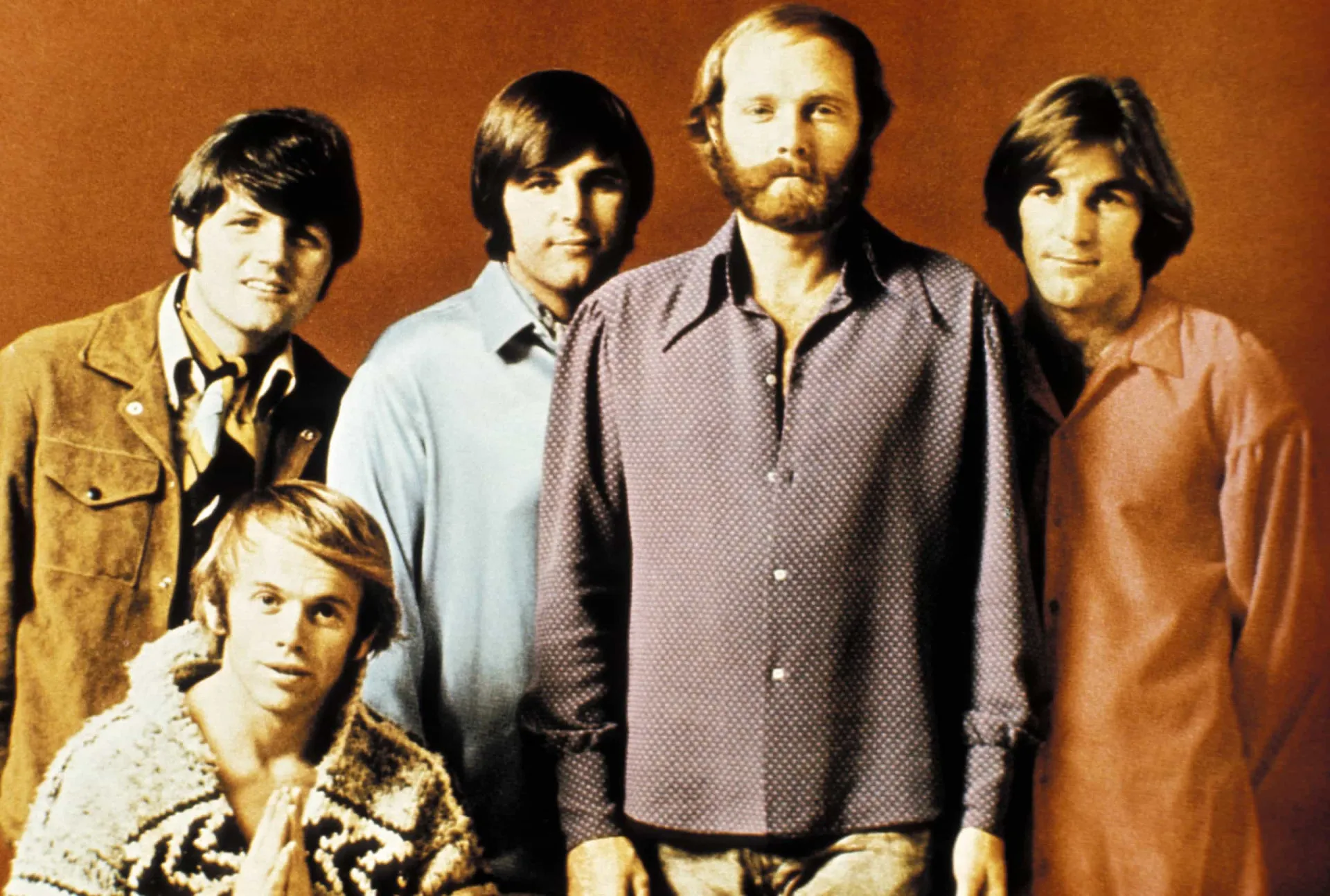 A banda The Beach Boys em uma foto clássica dos anos 60, em uma praia com pranchas de surfe.