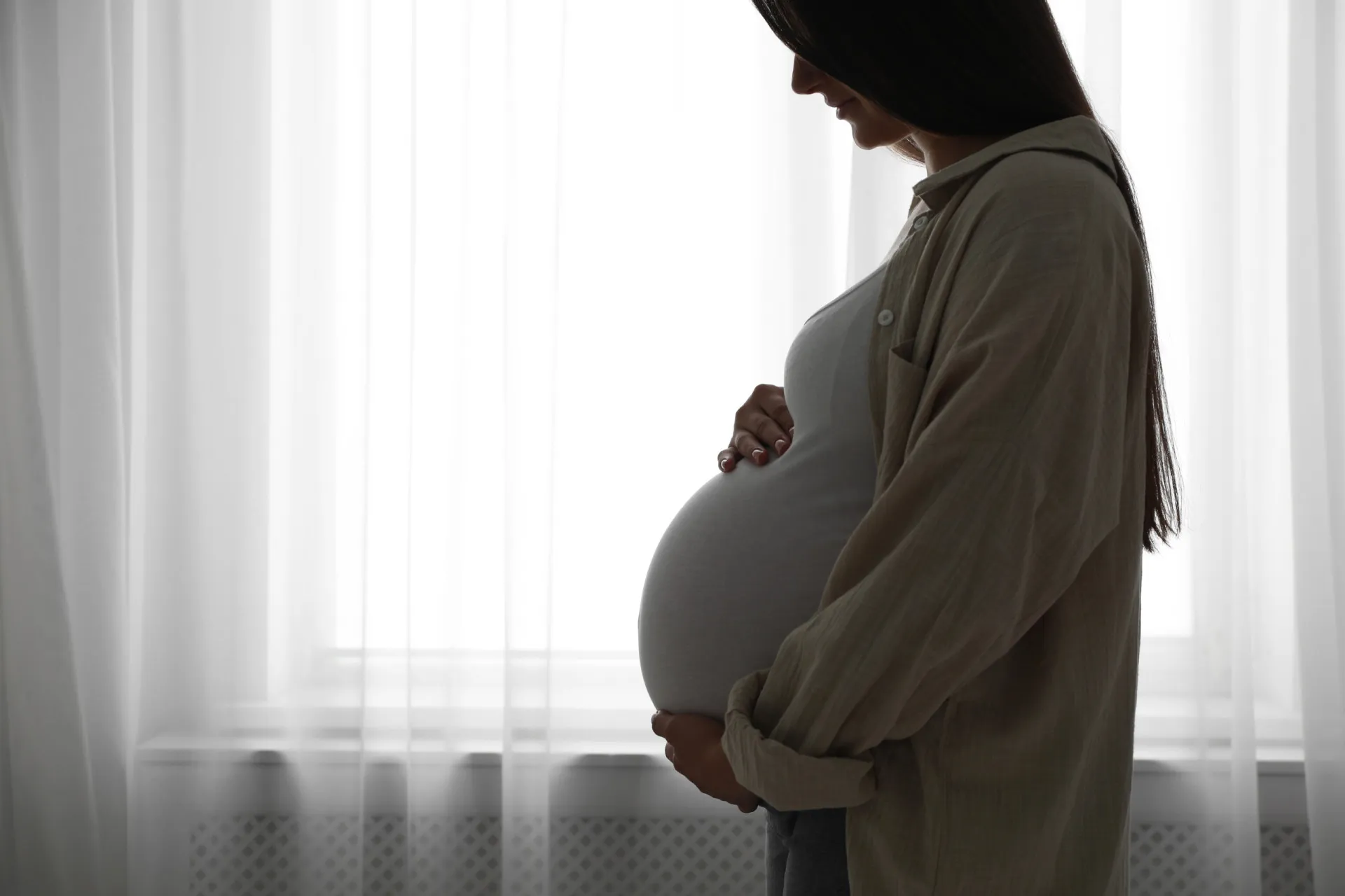 Mulher grávida acariciando a barriga, em um ambiente tranquilo e seguro.