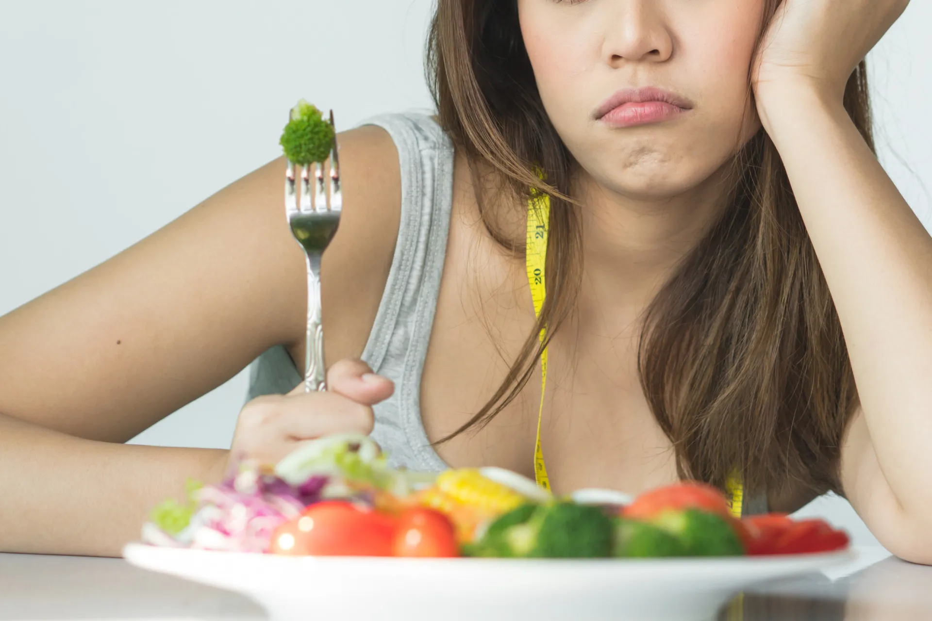 Uma pessoa comendo uma salada no almoço, com outras opções de refeições saudáveis visíveis ao redor.