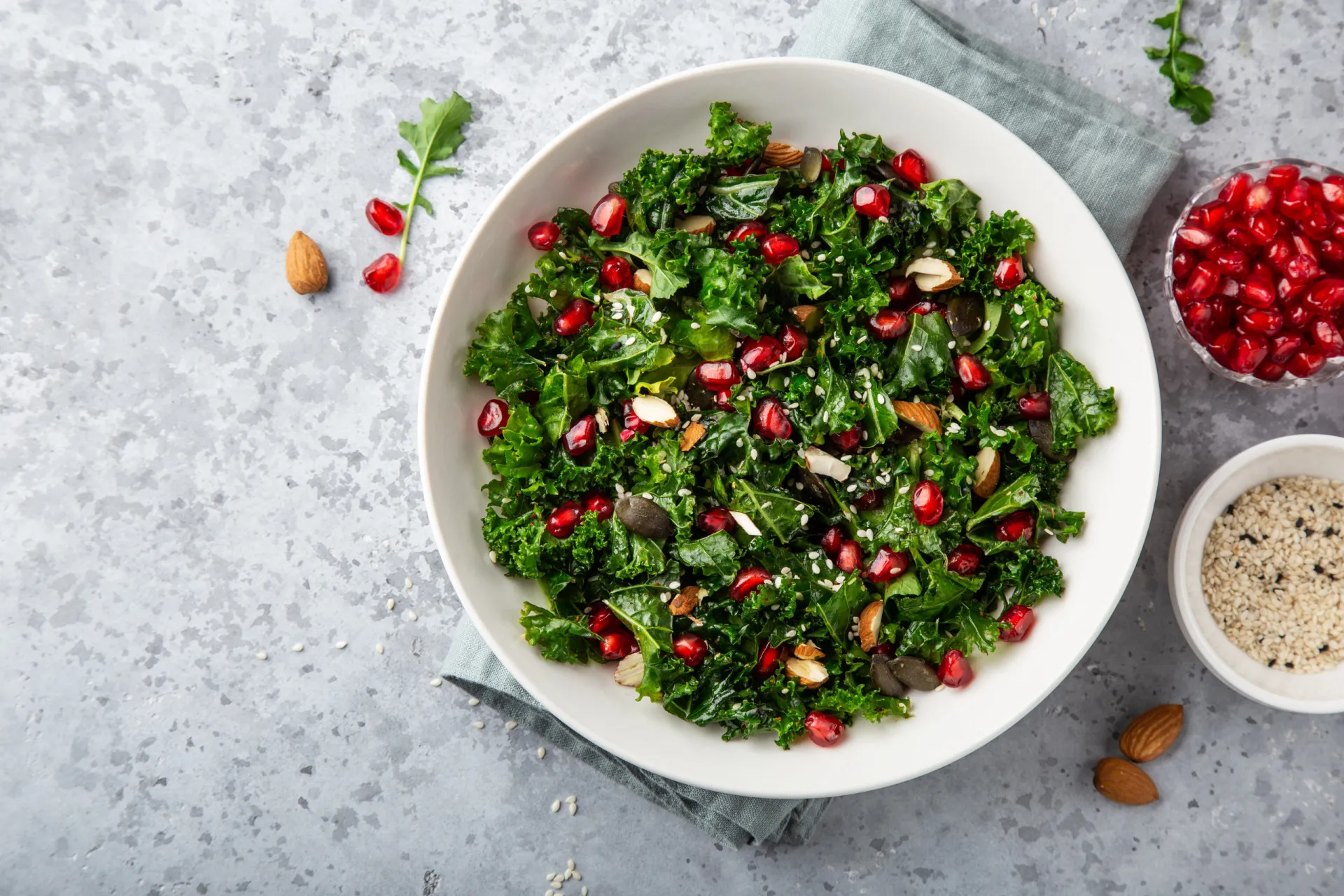Um frasco de medicamento anticoagulante ao lado de vegetais de folhas verdes escuras como couve e espinafre.