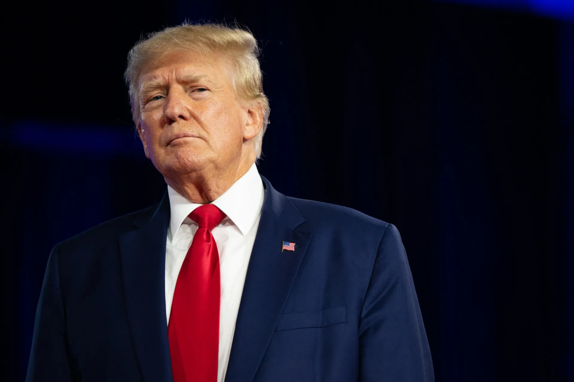 Donald Trump gesticulando durante um discurso, com o selo presidencial ao fundo.
