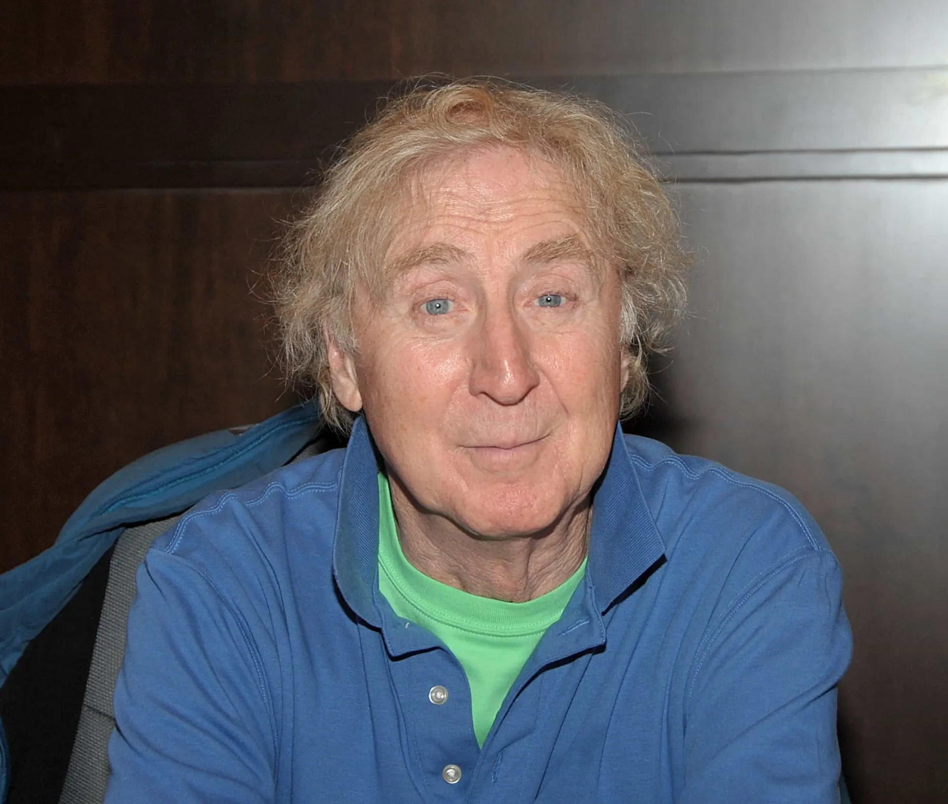 Gene Wilder com um sorriso gentil e olhos expressivos em um retrato.