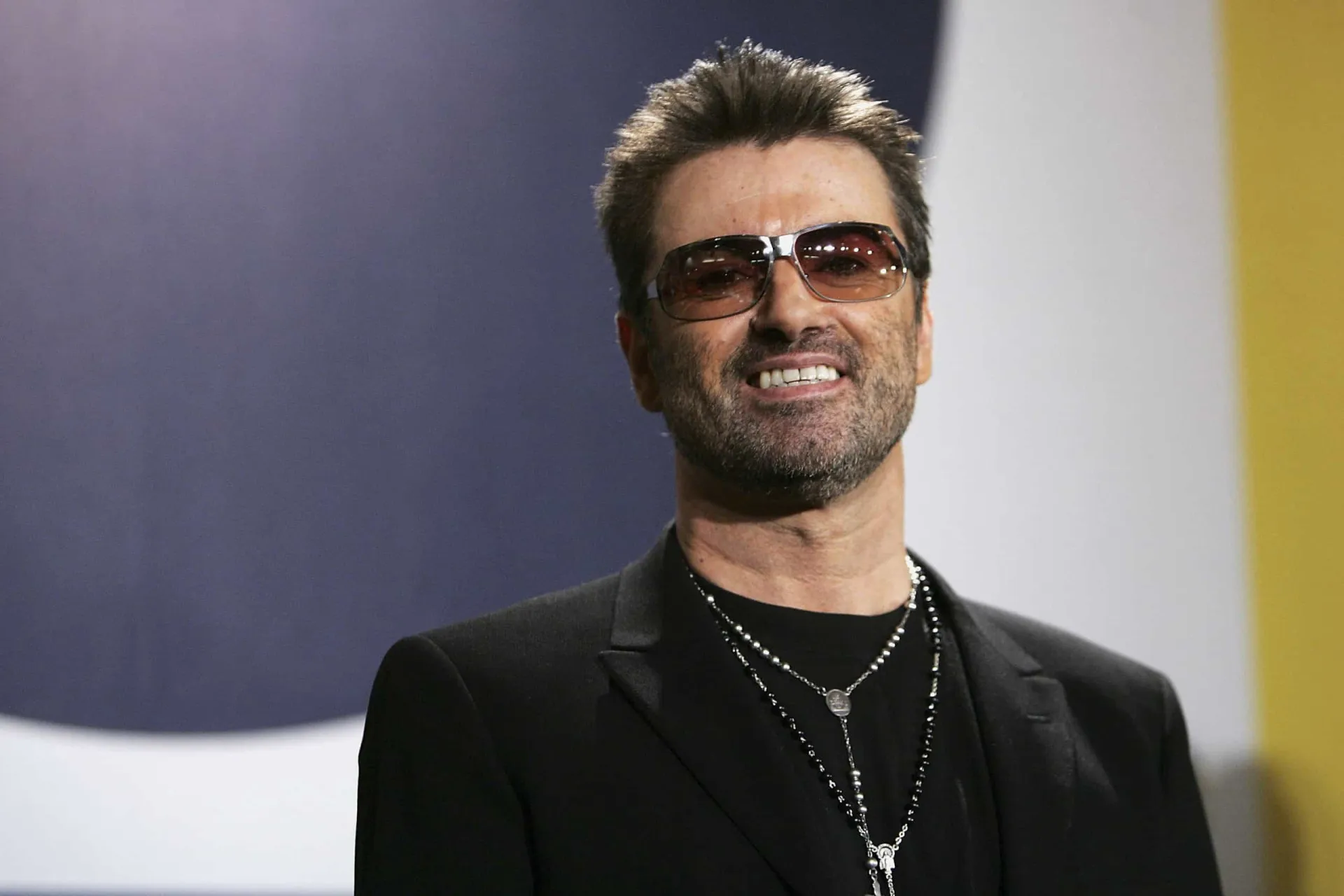 George Michael se apresentando no palco, cantando com paixão.