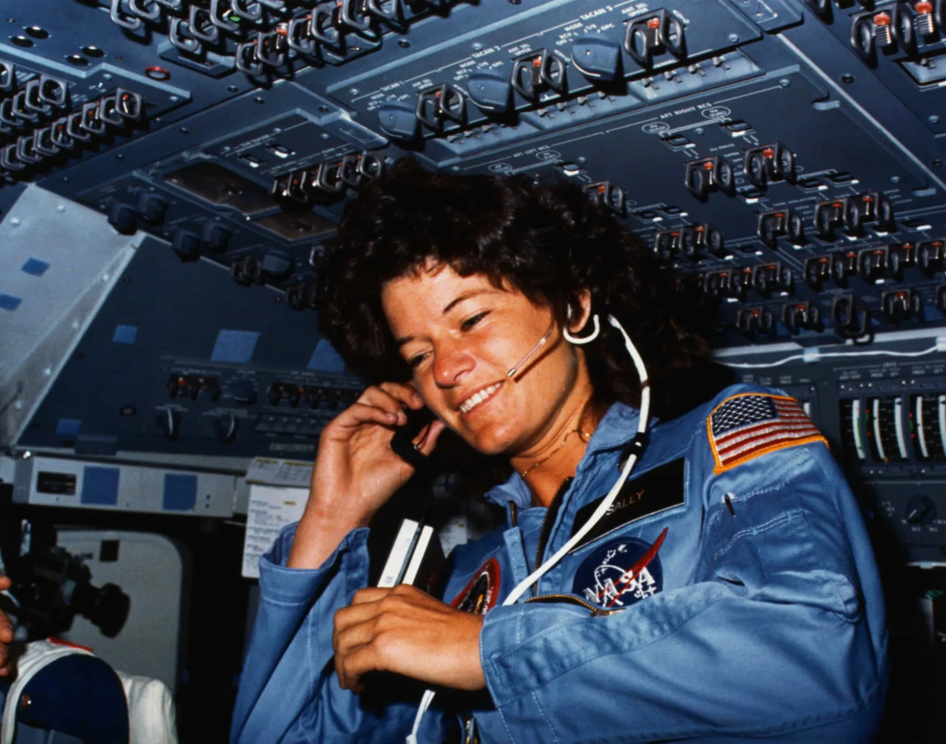 A astronauta Sally Ride sorrindo em seu traje espacial da NASA.