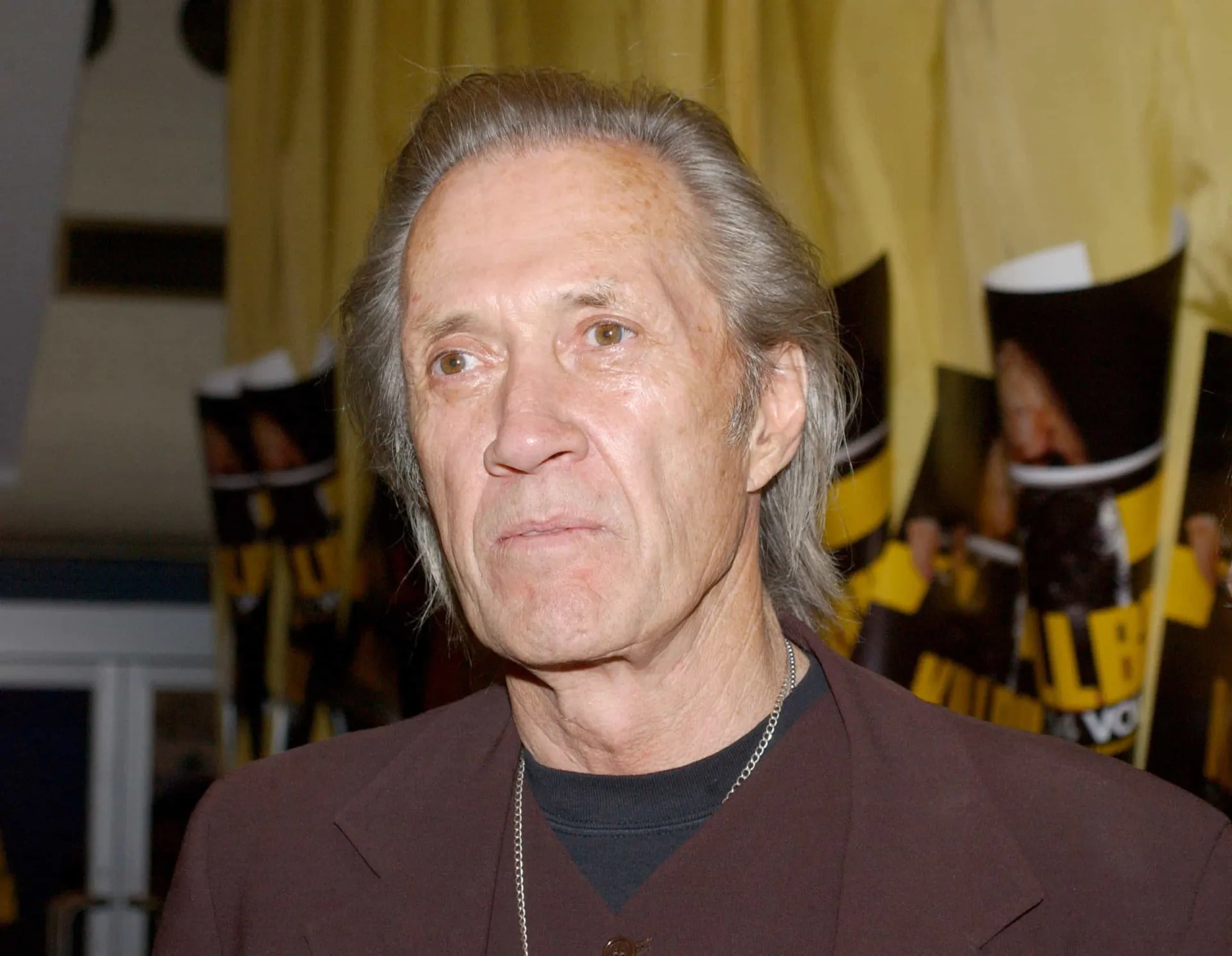 David Carradine em um evento, com um sorriso enigmático no rosto.