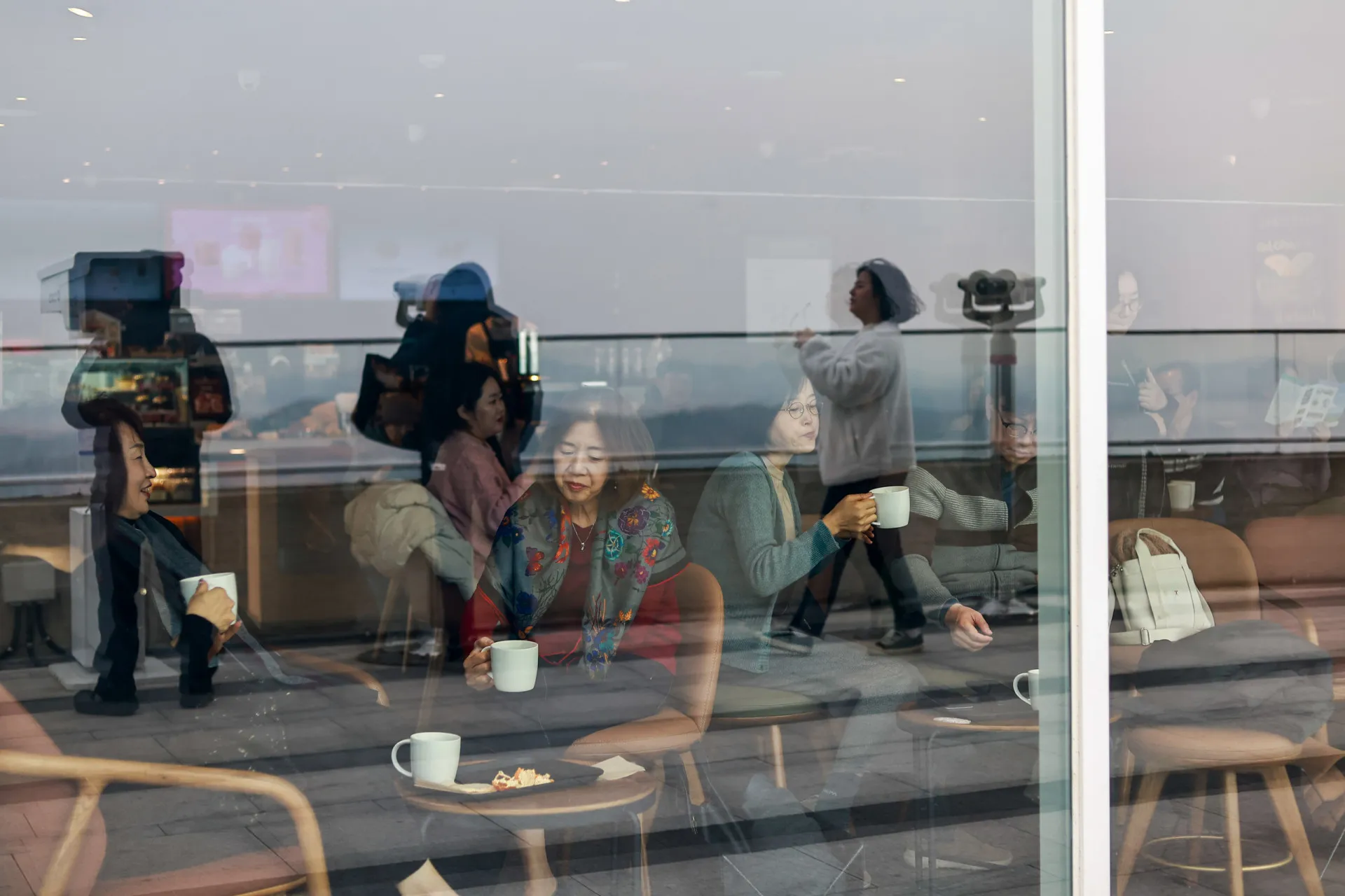 Pessoas em uma cafeteria moderna na Coreia do Sul, com a Coreia do Norte visível ao fundo.