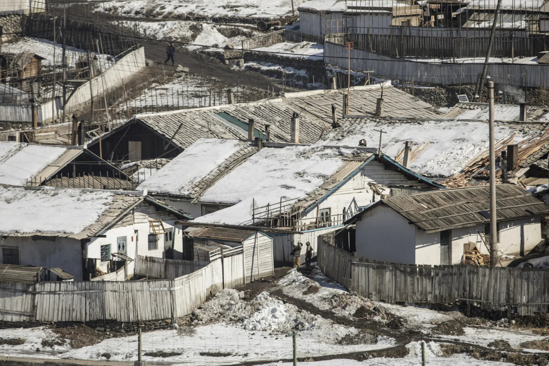 Crianças brincando em frente a casas simples na cidade de Hyesan, Coreia do Norte.