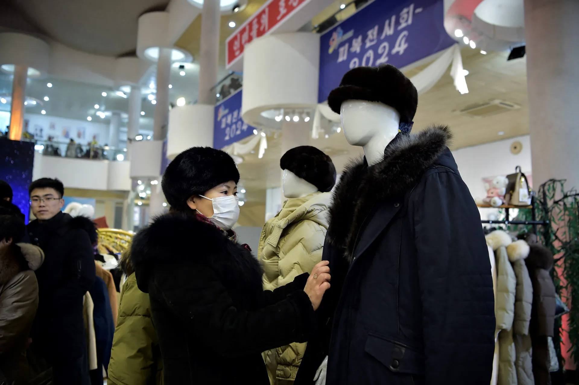 Mulheres norte-coreanas observando roupas em uma feira de moda em Pyongyang.