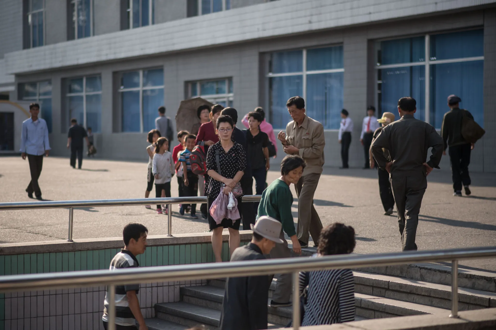 Pedestres caminhando e usando uma passagem subterrânea em uma rua movimentada de Pyongyang.