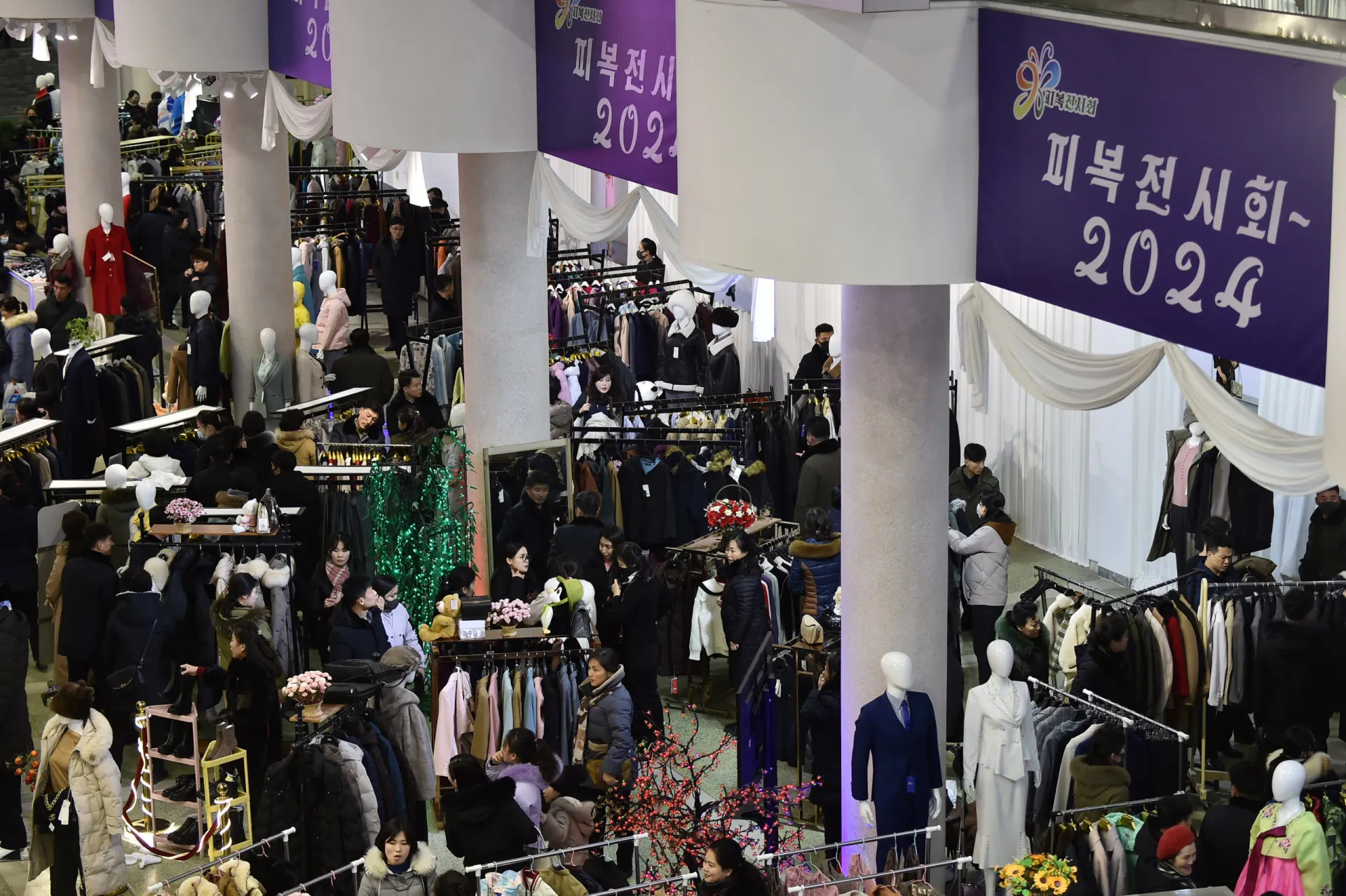 Multidão de pessoas circulando em uma feira de moda na capital da Coreia do Norte.