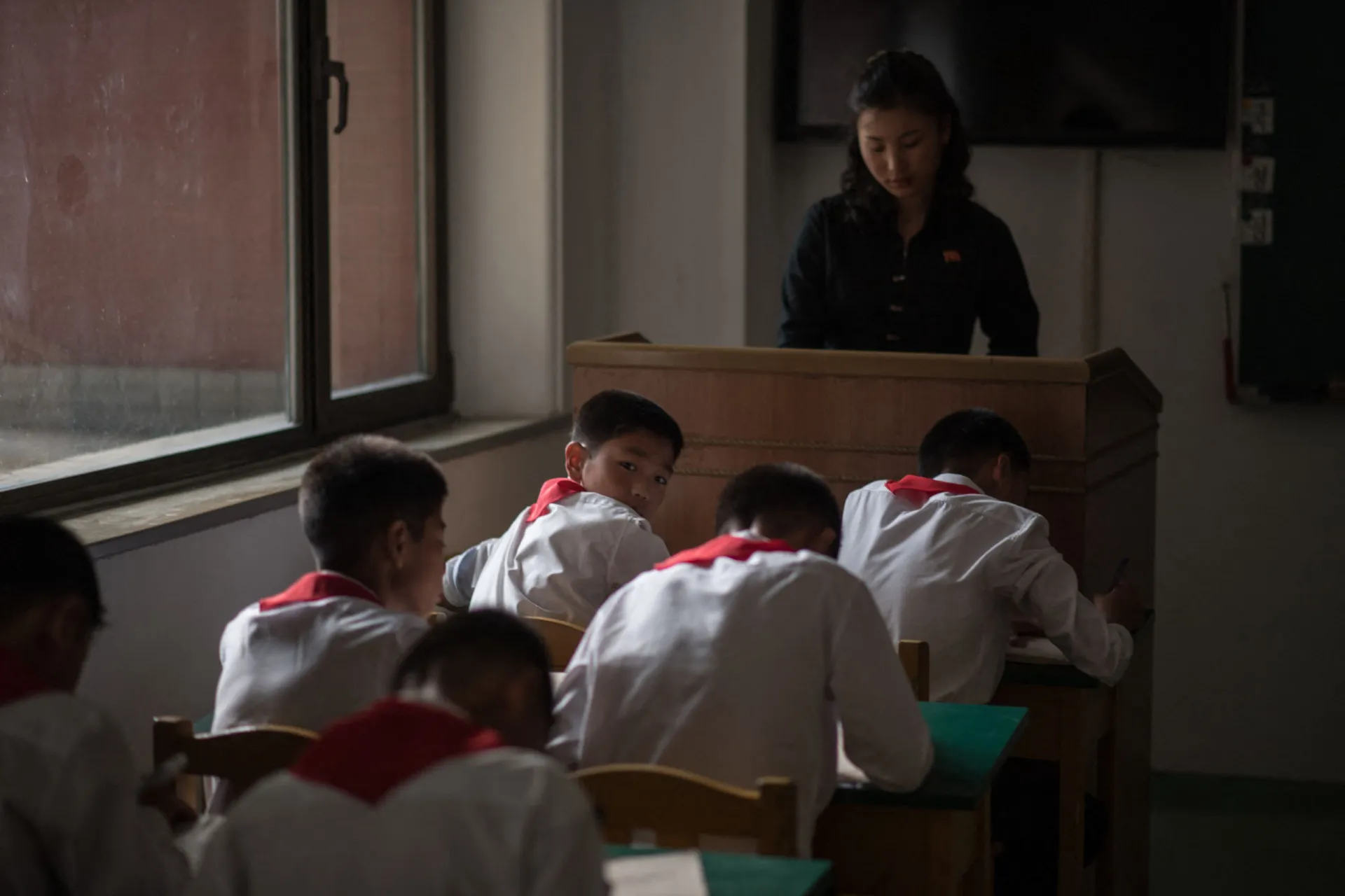 Alunos em uma sala de aula em Pyongyang fazendo um teste, com um deles olhando para a câmera.