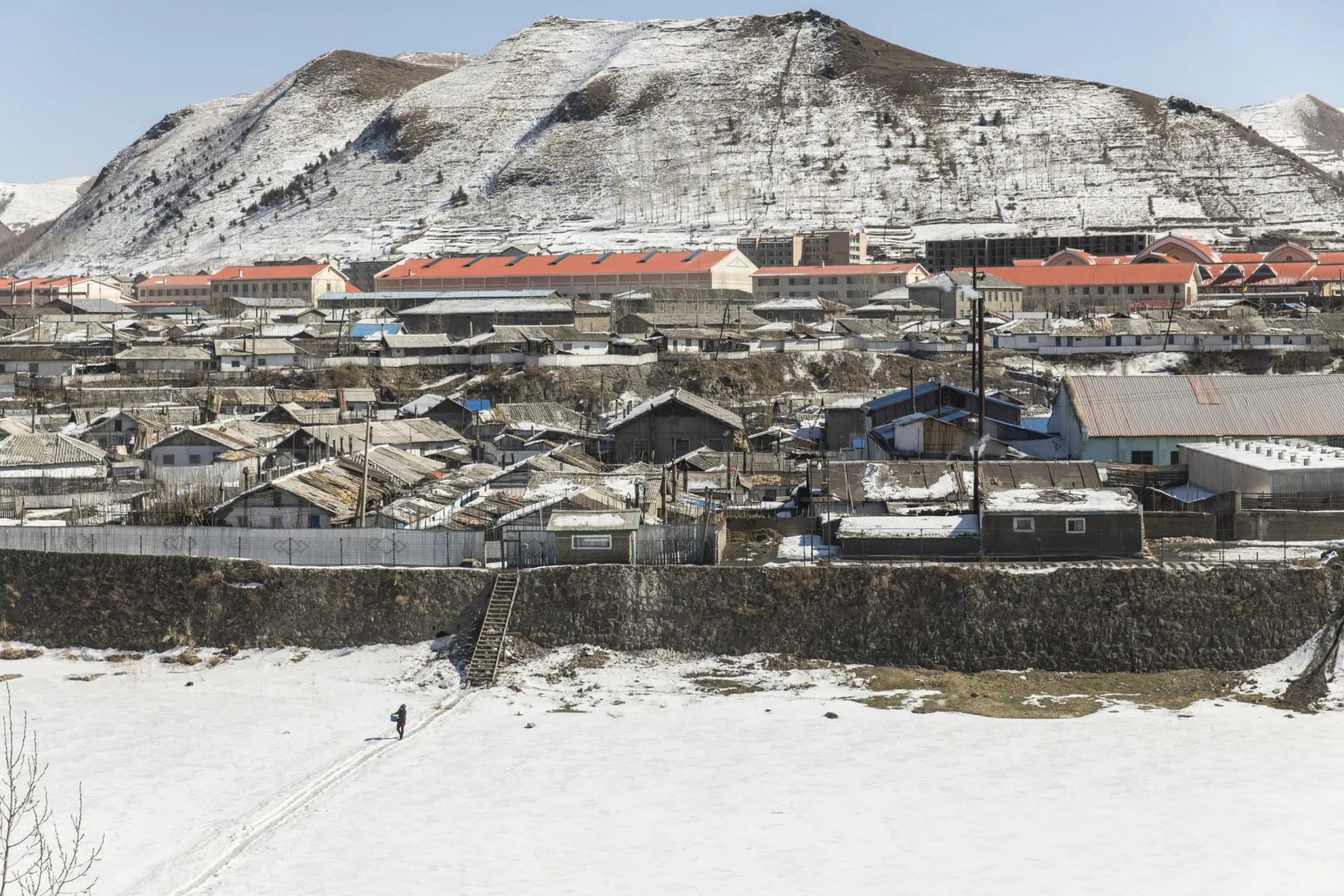 Fotógrafo capturando imagens de casas e prédios baixos em Hyesan, Coreia do Norte, a partir da China.