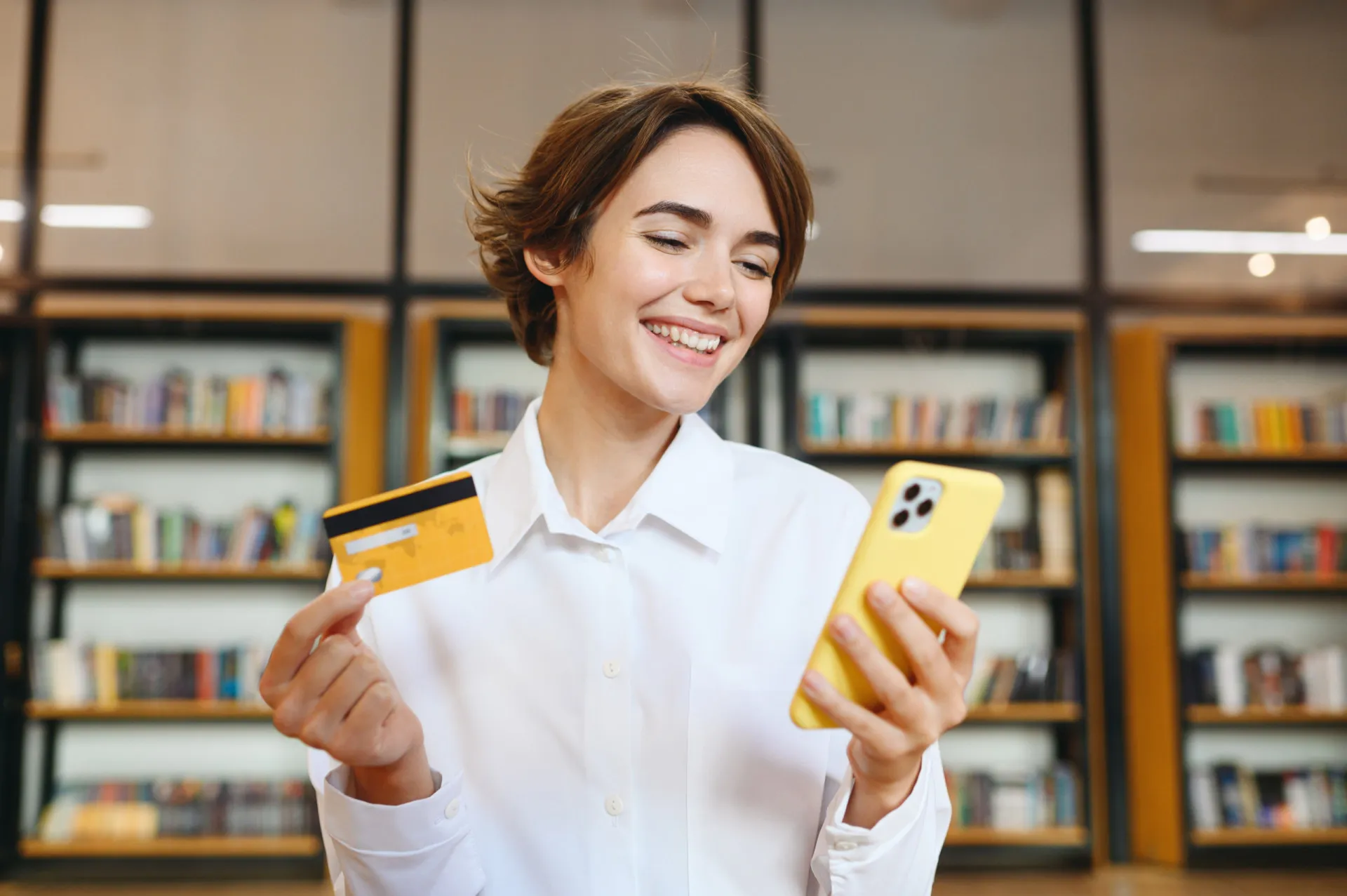 Uma mulher sorrindo enquanto faz compras online pelo celular, cercada por sacolas de compras.