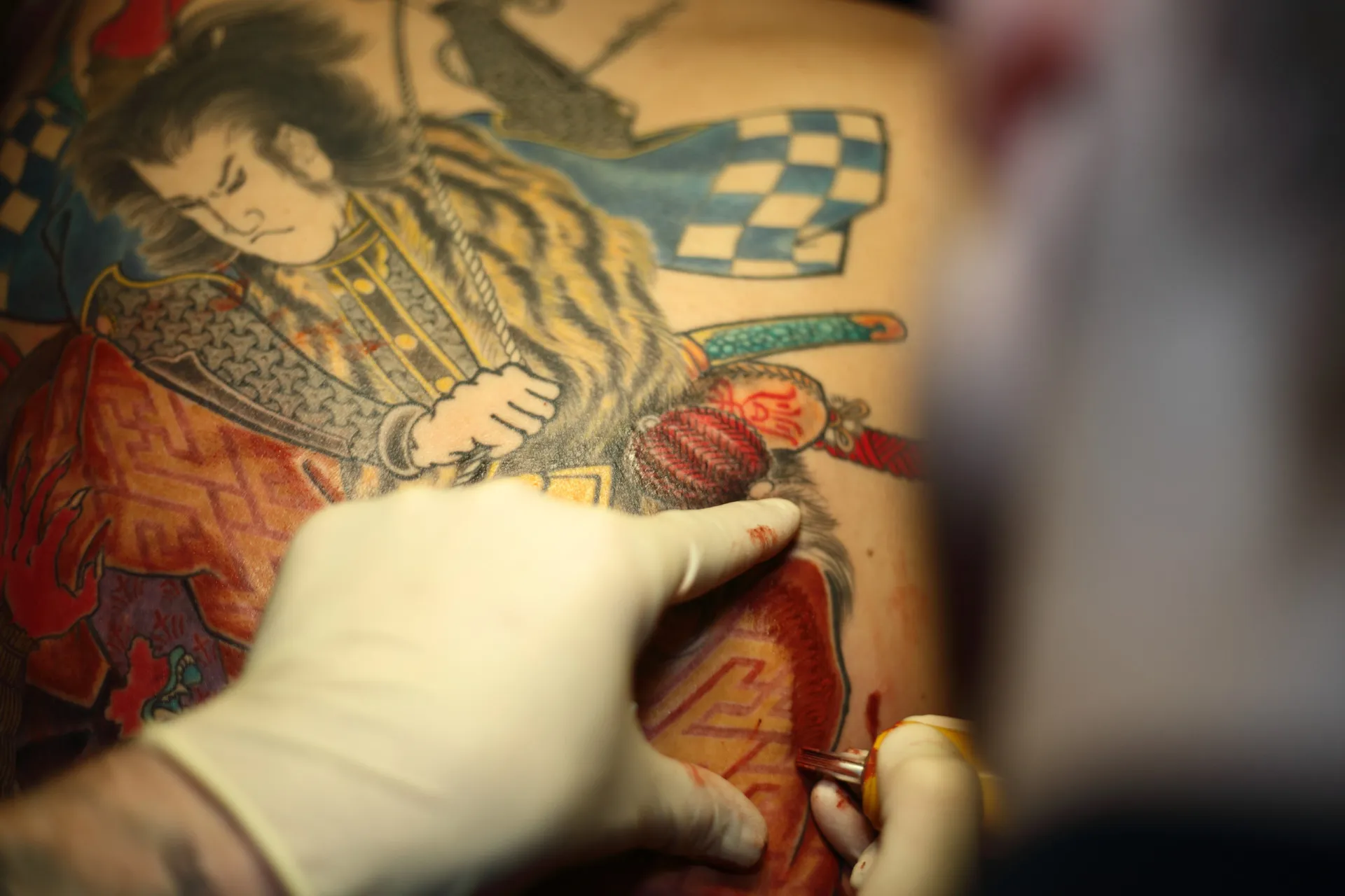 Close-up de uma elaborada tatuagem nas costas de um membro da Yakuza, cheia de simbolismo.