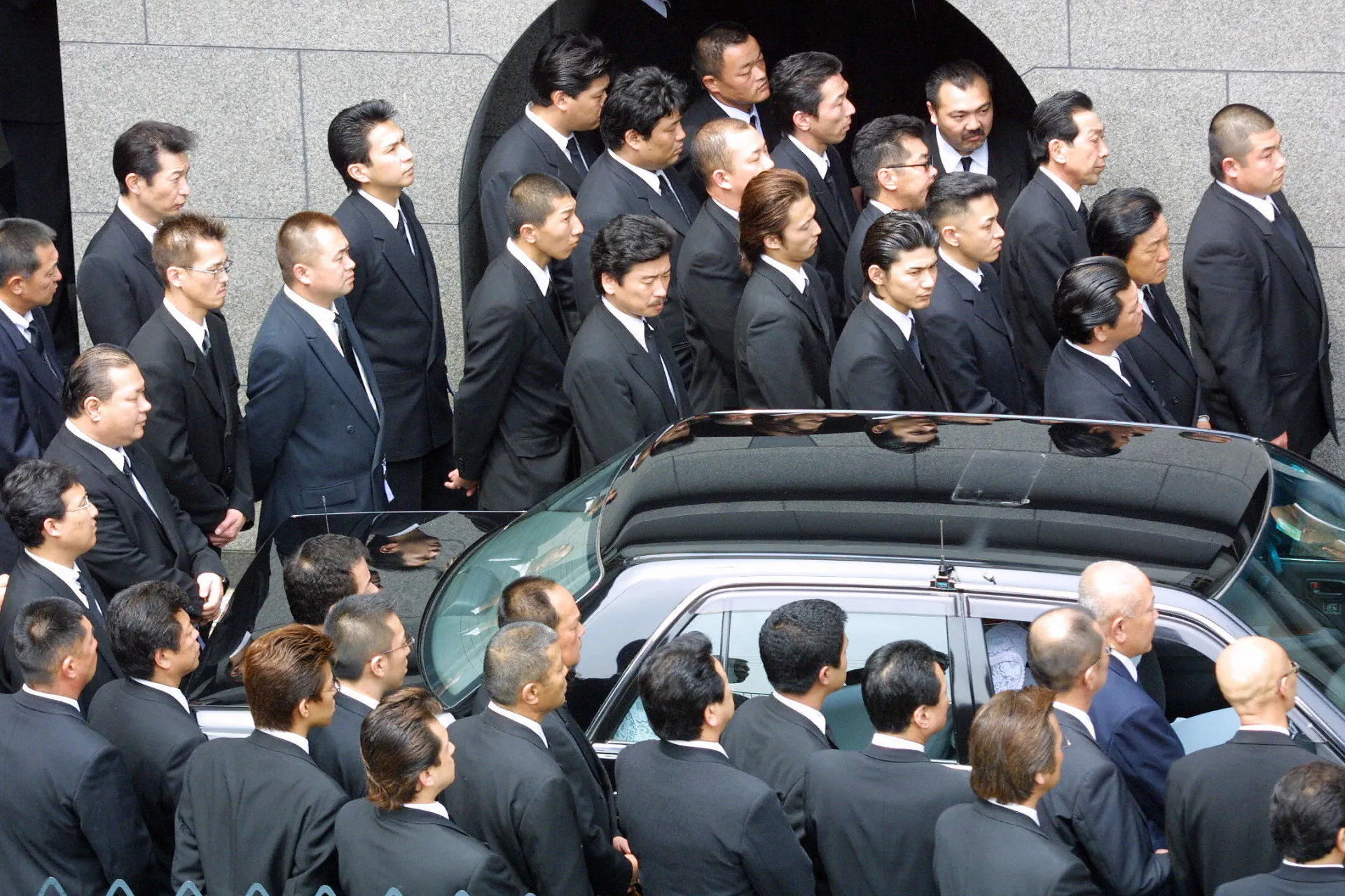 Um chefe da Yakuza (oyabun) cercado por seus subordinados (kobun), demonstrando a hierarquia rígida.