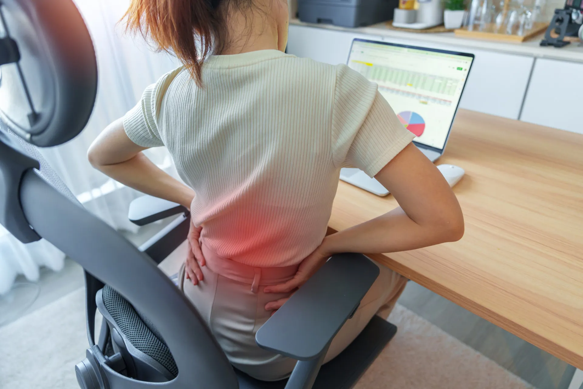 Pessoa sentada em uma cadeira ergonômica em frente a um monitor na altura correta.