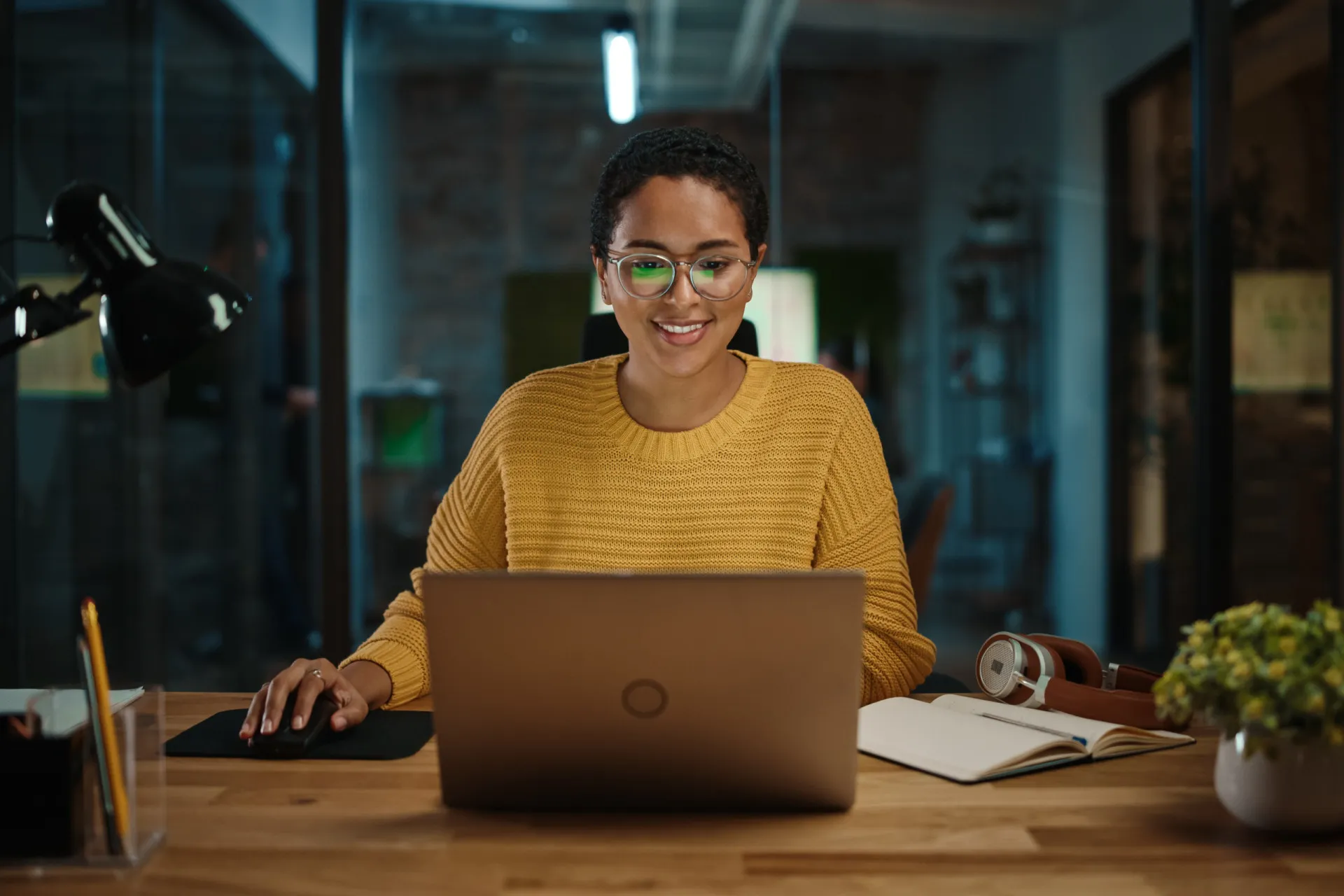 Escritório bem iluminado, com luz natural e uma luminária de mesa para evitar reflexos na tela.