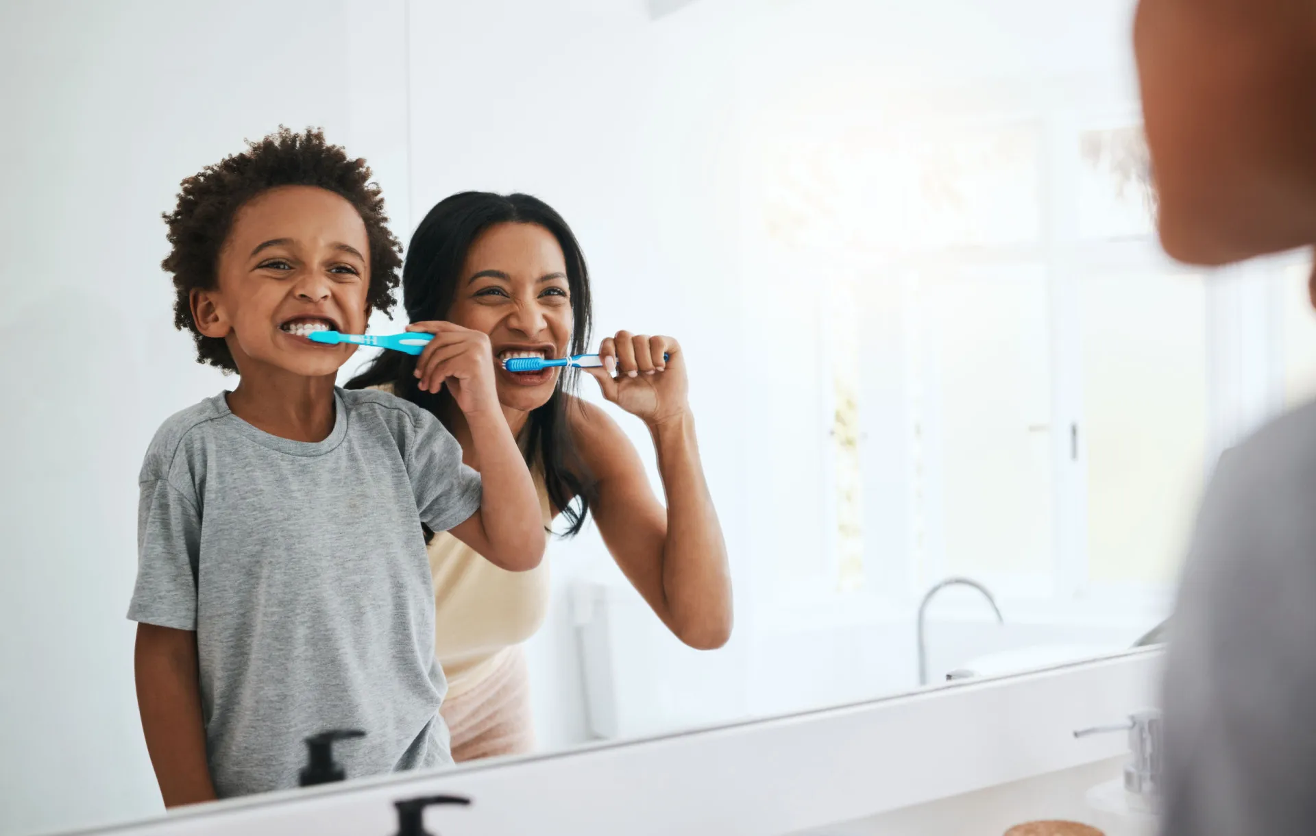 Uma criança escovando os dentes em frente ao espelho, um hábito diário de cuidado com a saúde.