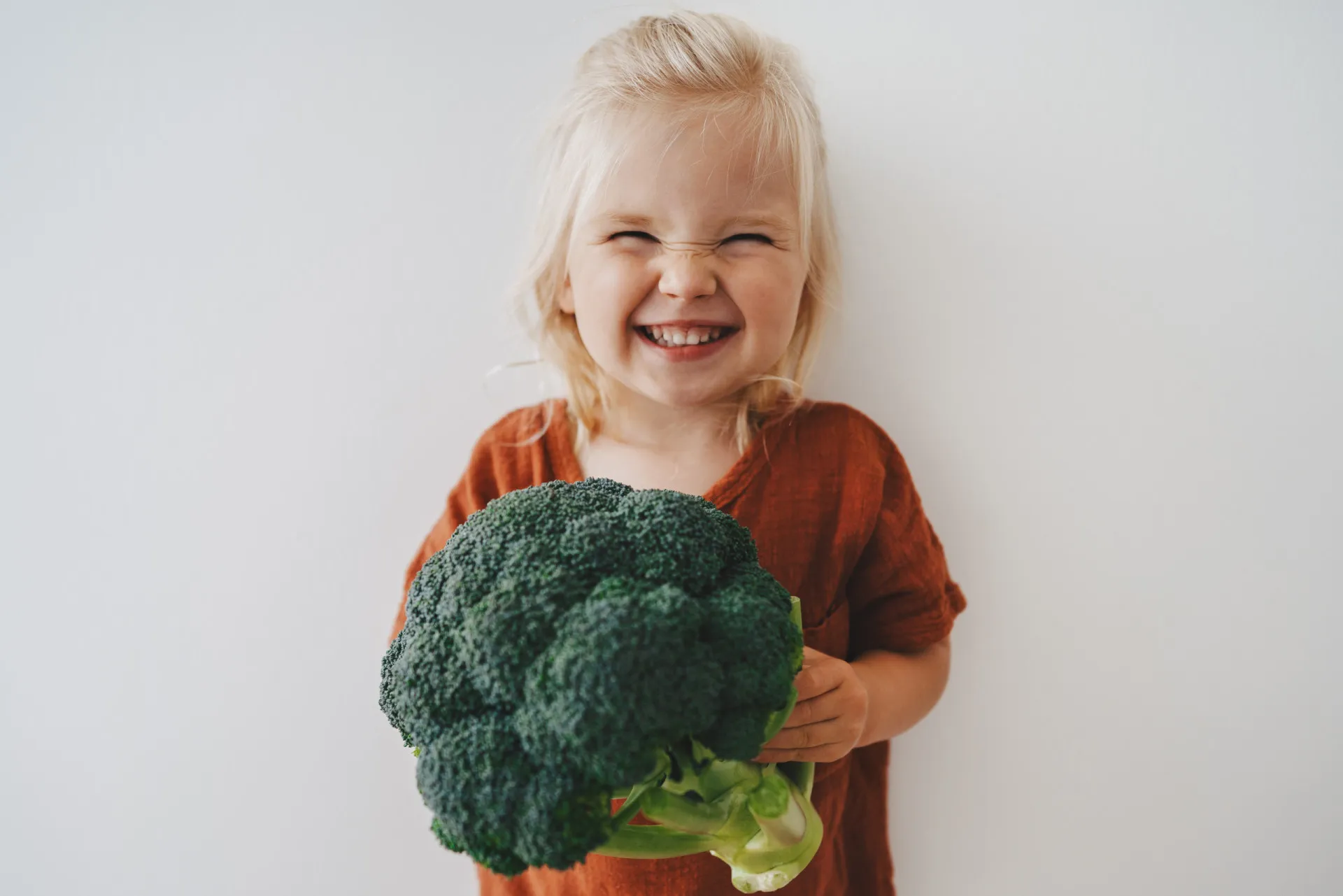 Uma criança comendo uma salada de vegetais coloridos com entusiasmo, aprendendo sobre alimentação saudável.